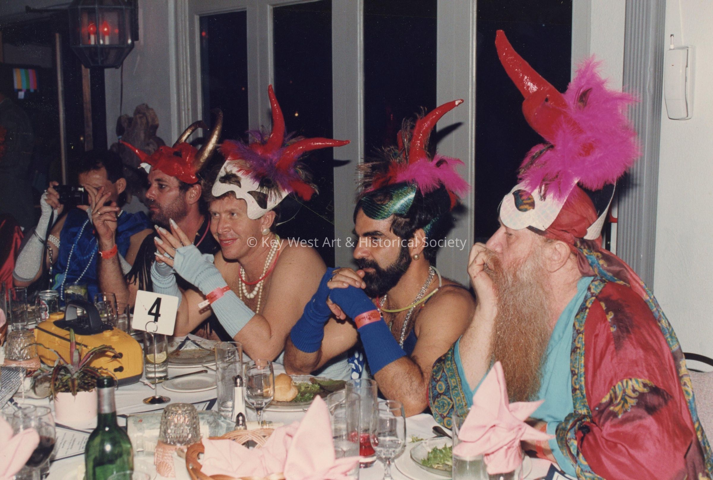 Five unknown men dressed up sitting at a table.