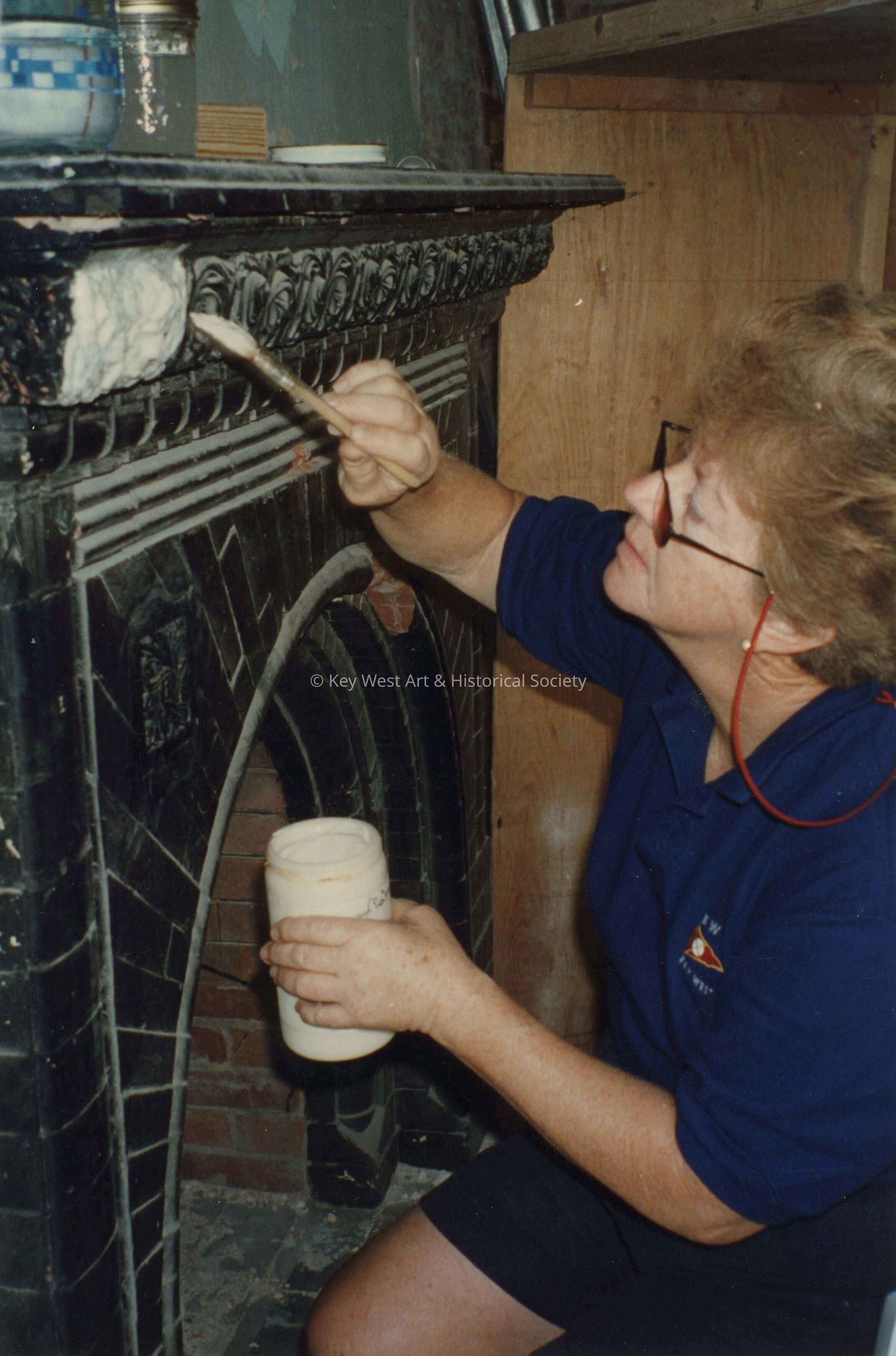 An unknown woman painting one of the fireplaces.