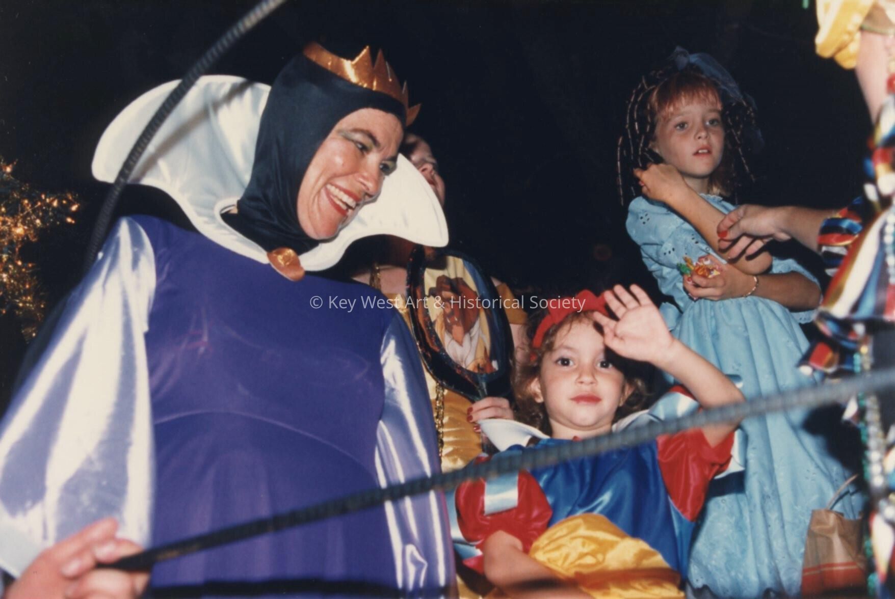 An unknown woman dressed up with two unknown kids dressed up.