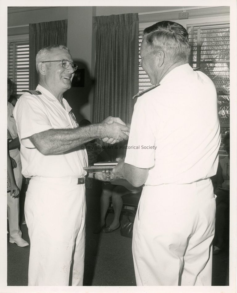 2 Men in uniform shaking hands and receiving a plaque