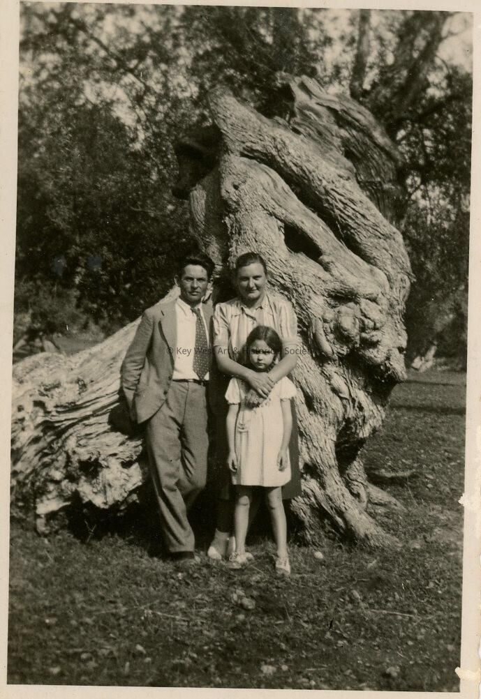 An unknown family standing near a tree