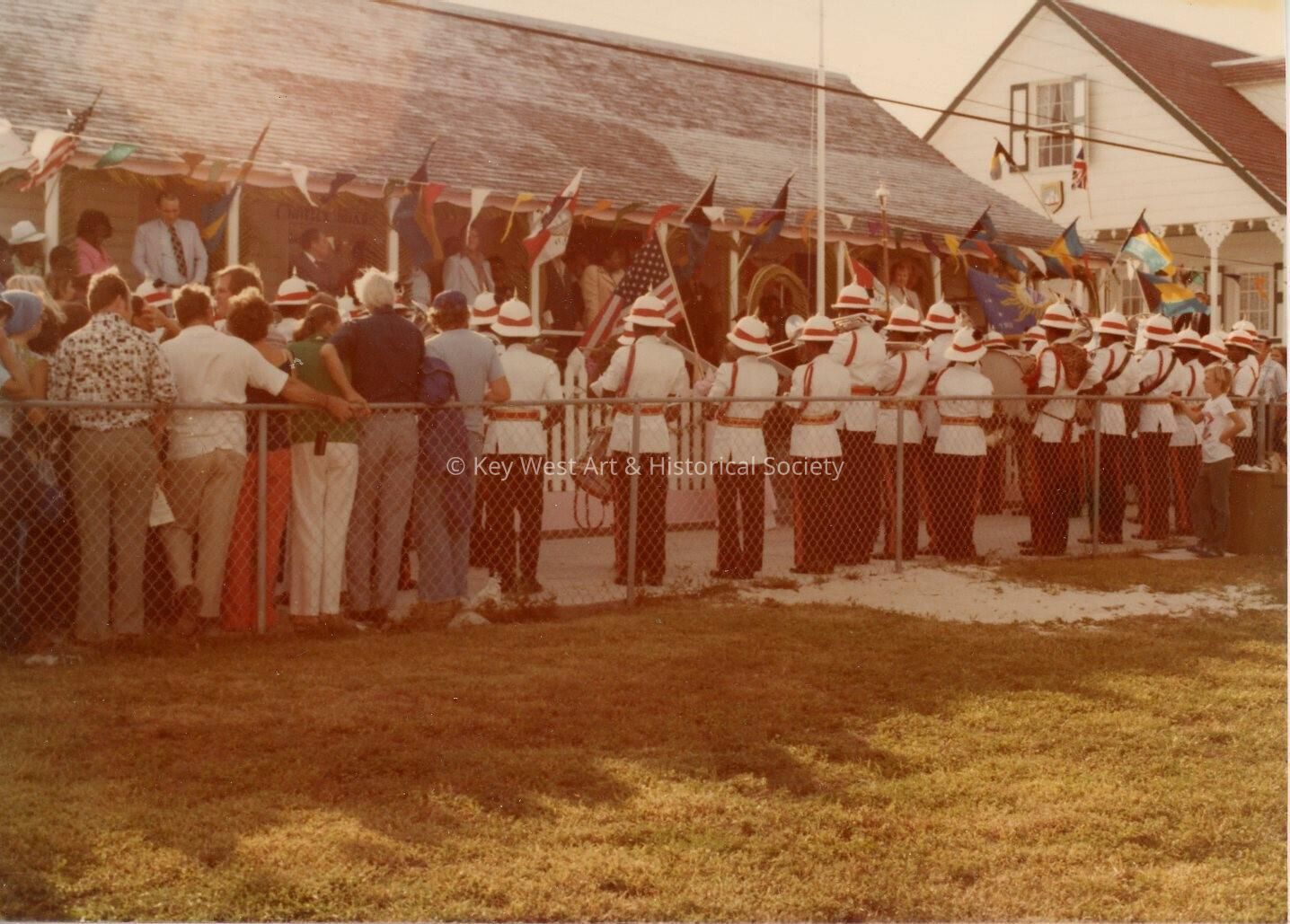 An unknown group of people standing against a fence