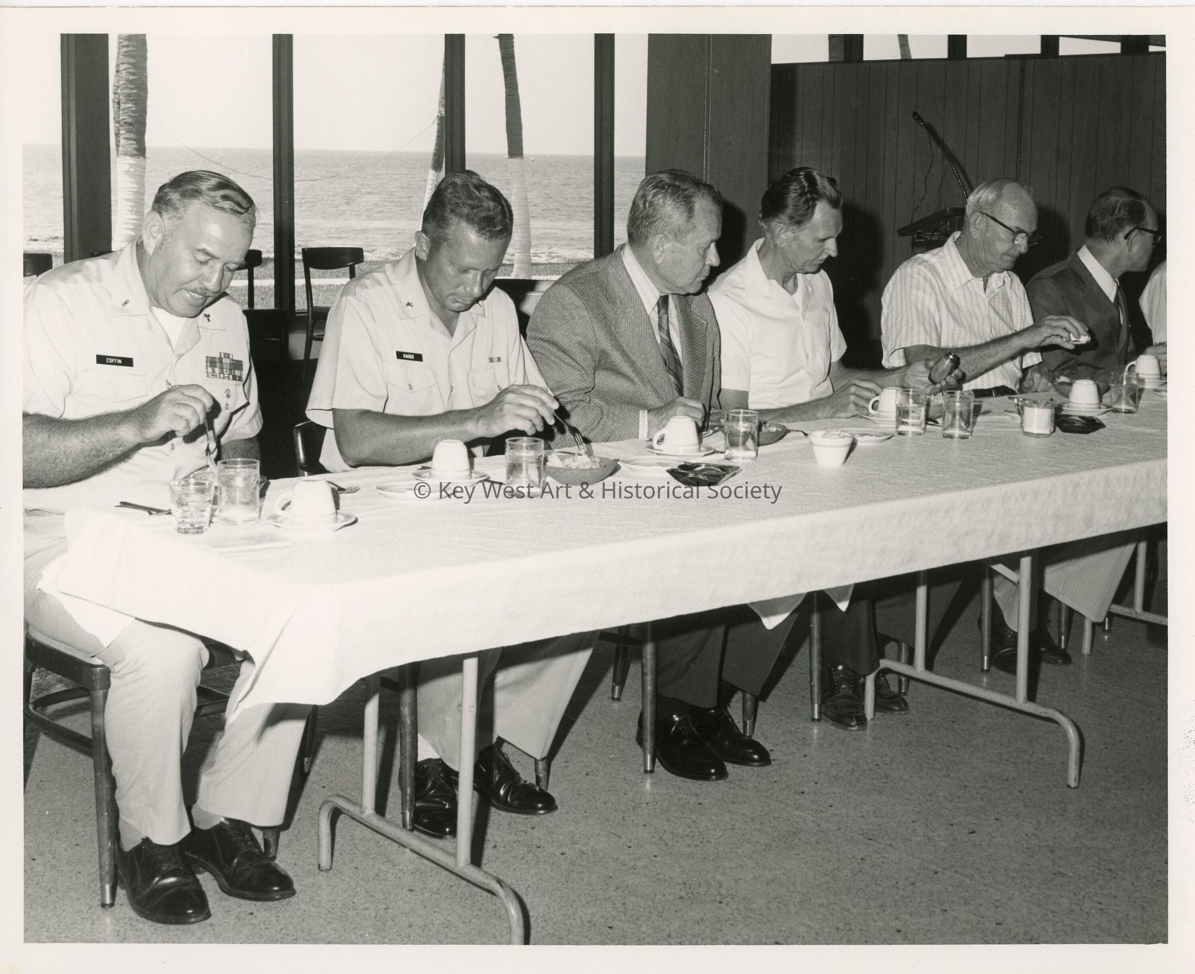 A group of men eating at a table, a few in uniform