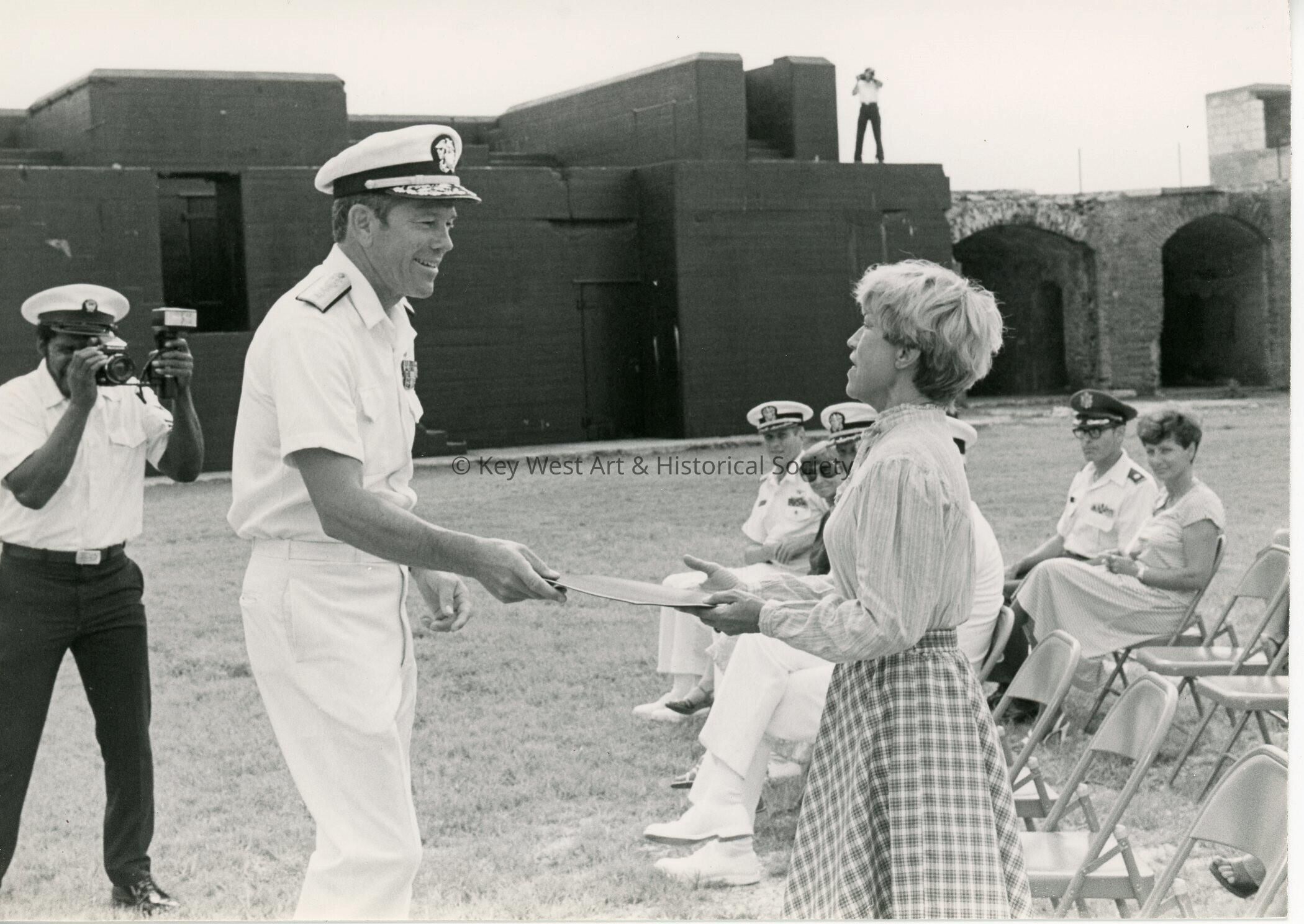 An unknown man in uniform handing a woman an award