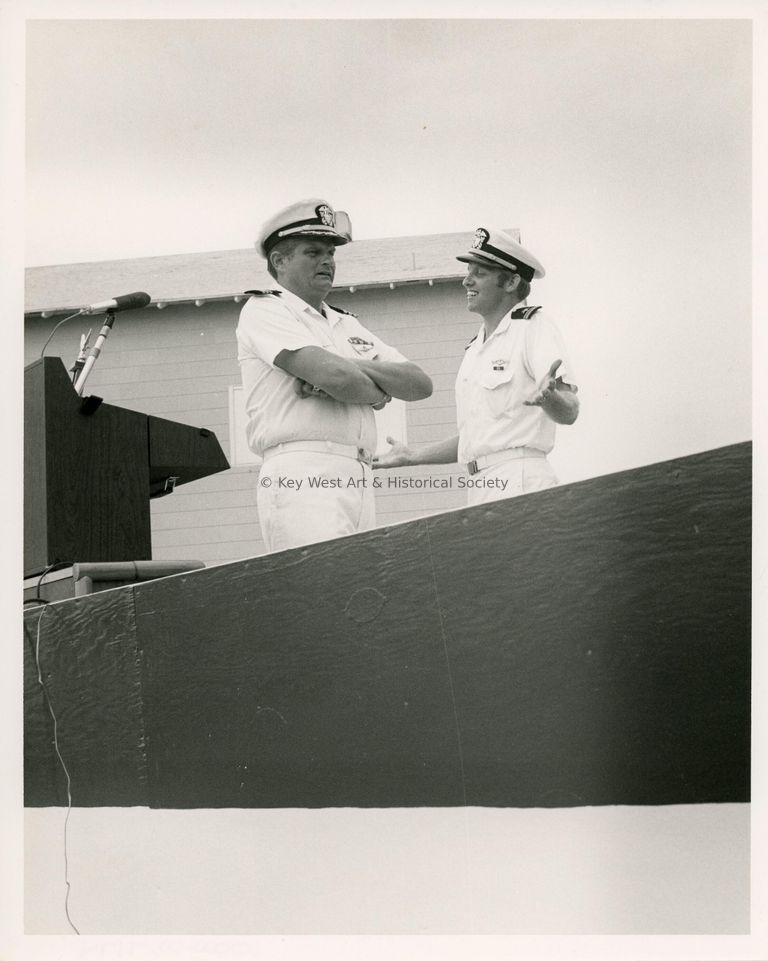 2 Men in uniform talking next to a podium