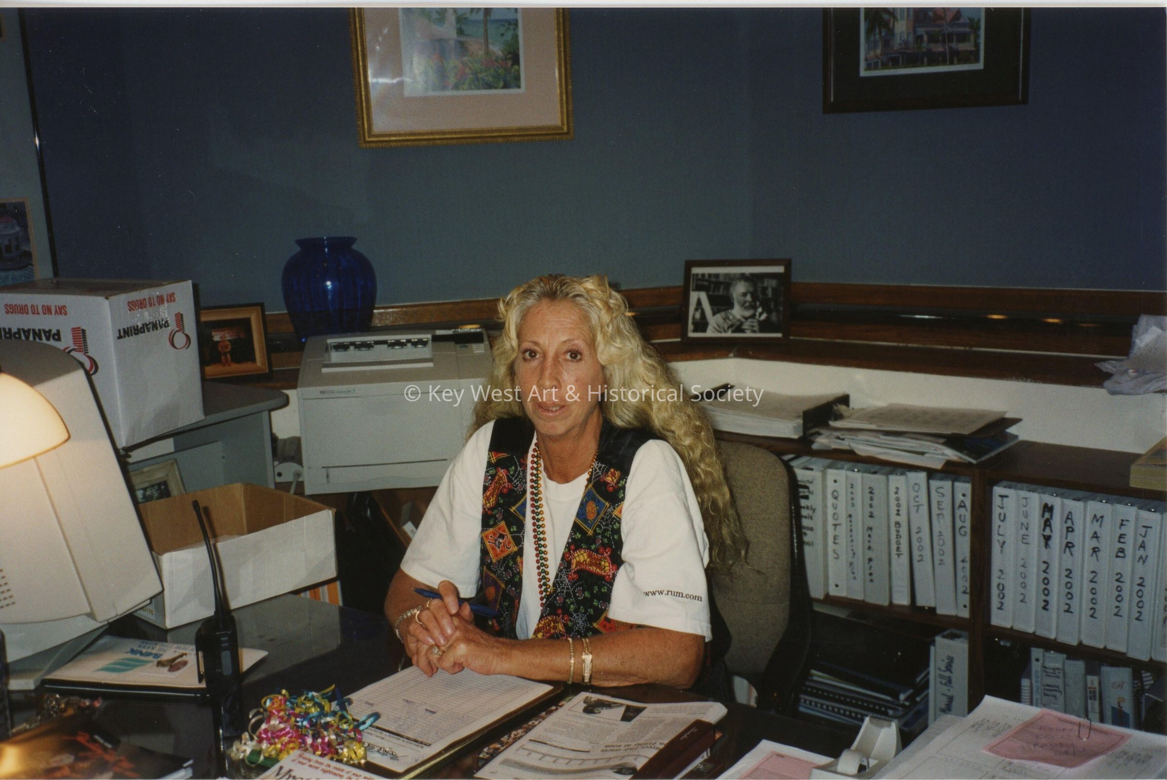 An unknown woman sitting at a desk.