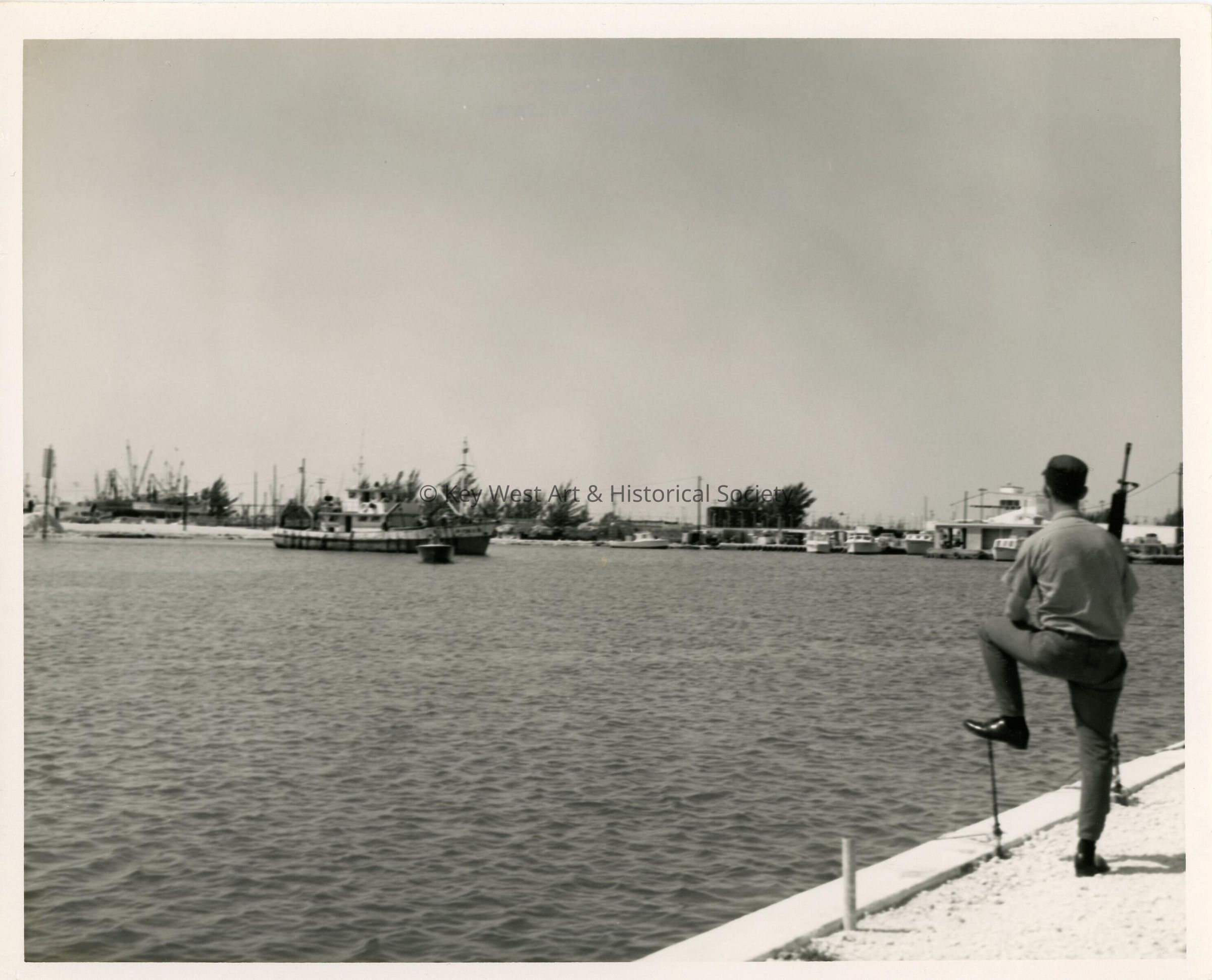 A view of the ocean with a ship and an unknown man in uniform standing on t