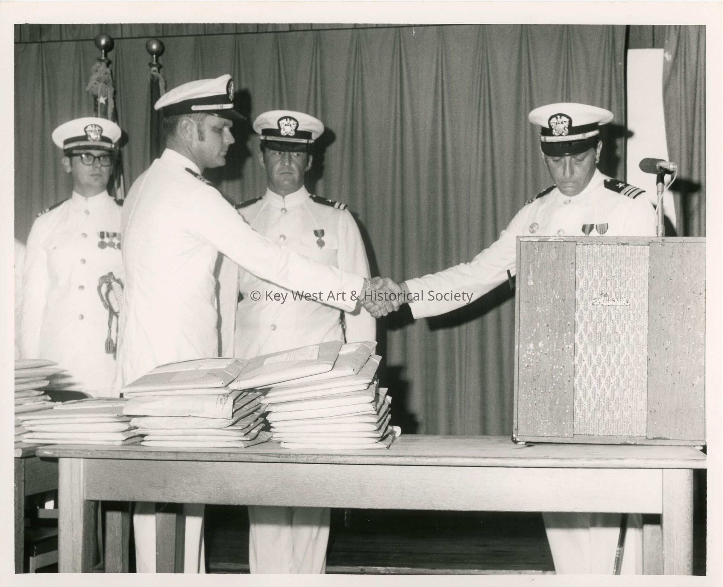 4 Unknown men in uniform standing near a podium