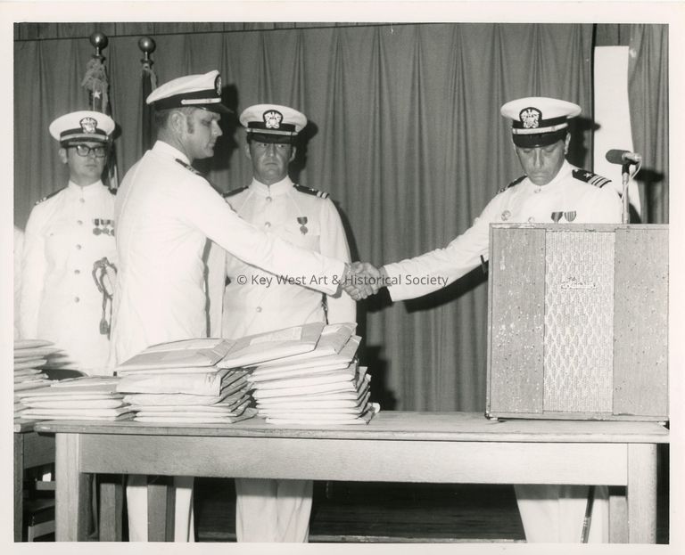 4 Unknown men in uniform standing near a podium