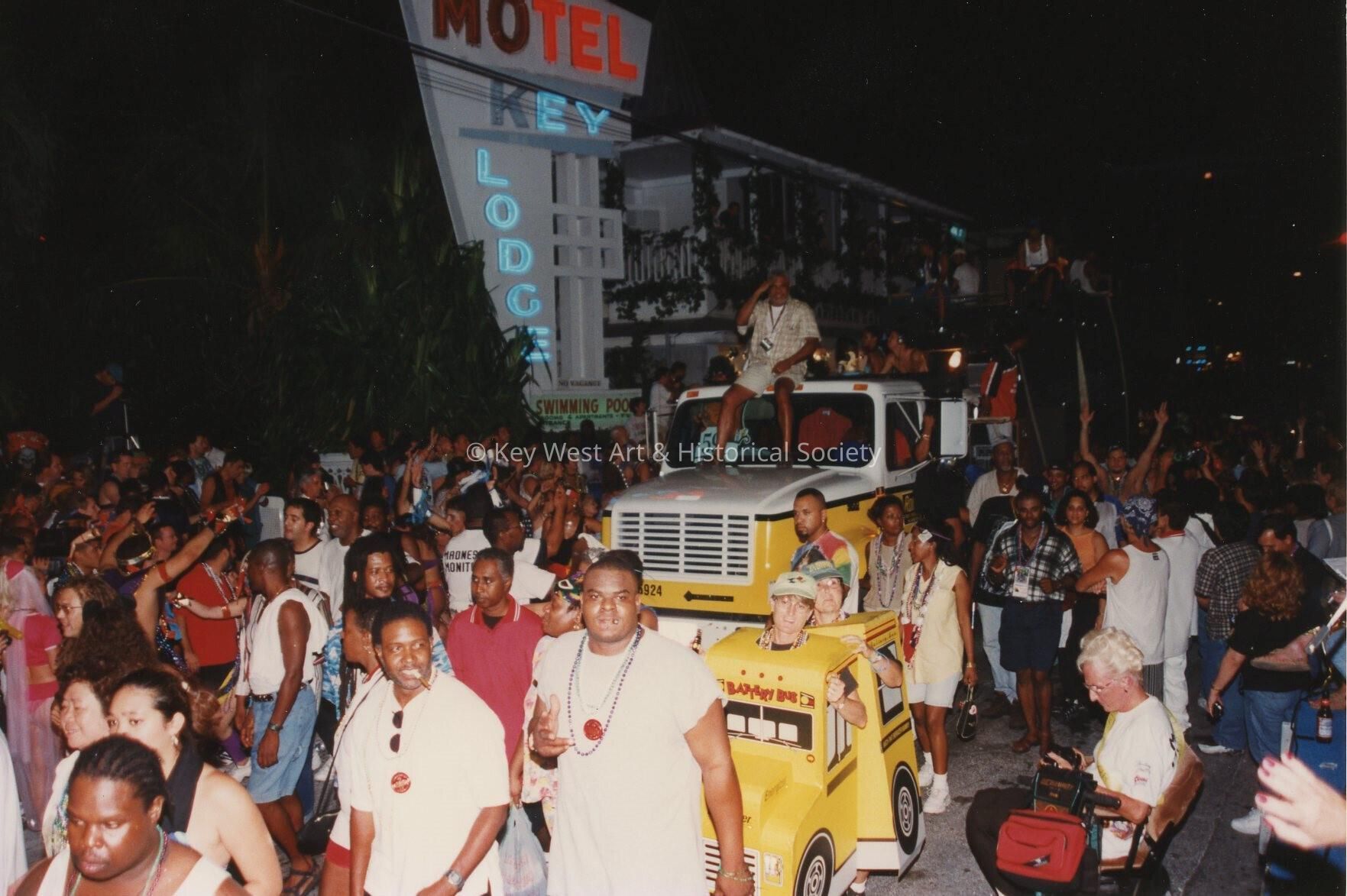 A huge group of unknown people walking in the street next to a float.
