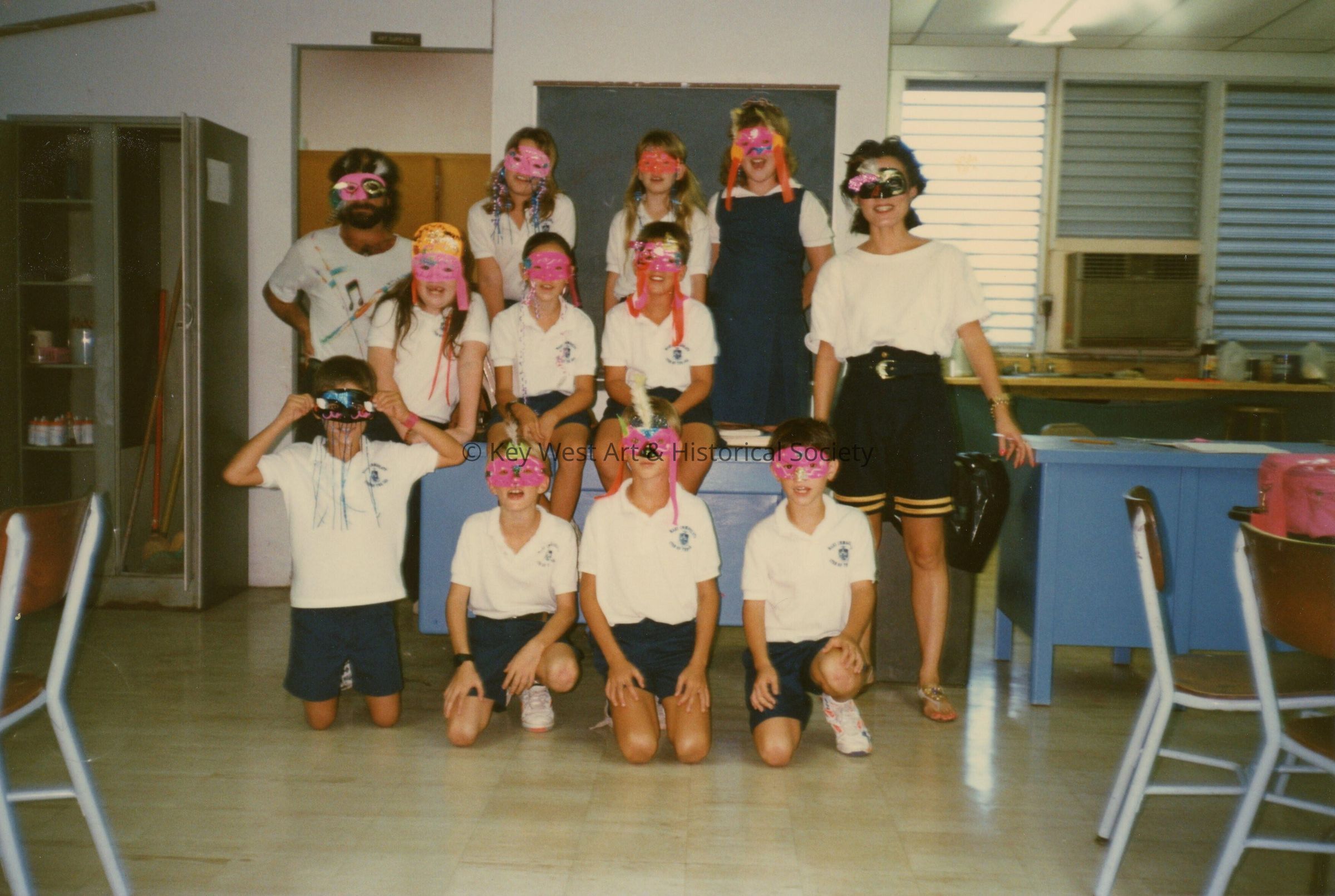A group of unknown school kids with two unknown adults all wearing face mas