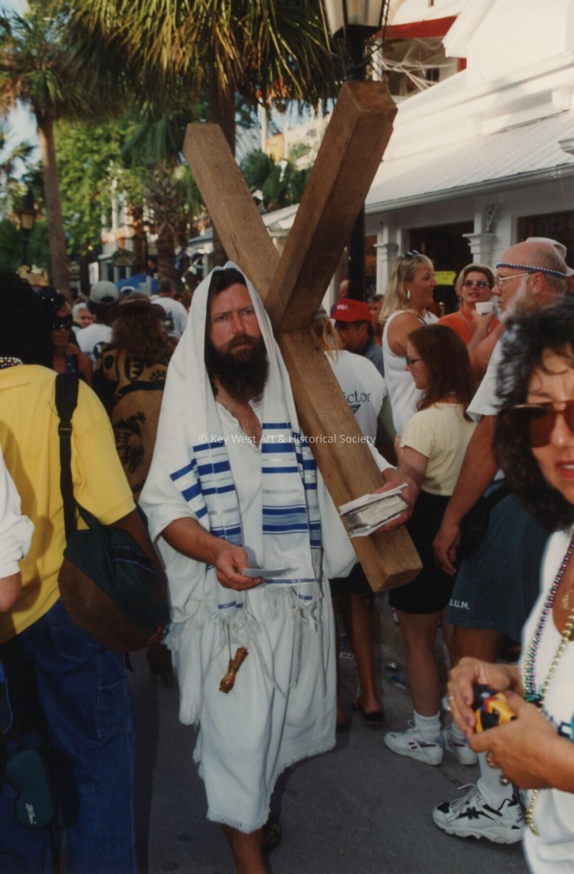 An unknown man carrying a wooden cross.