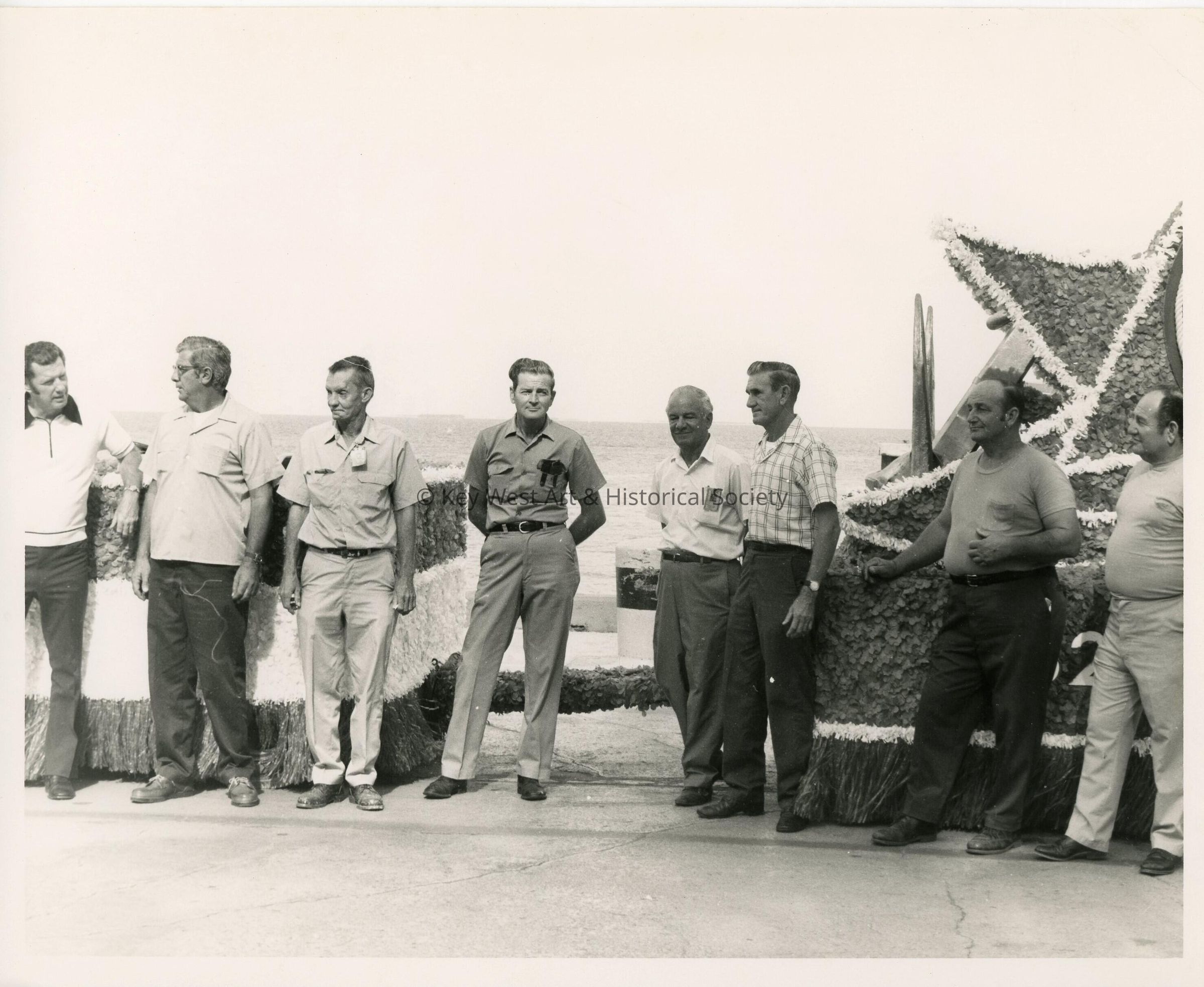 A group of unknown men standing  around a float