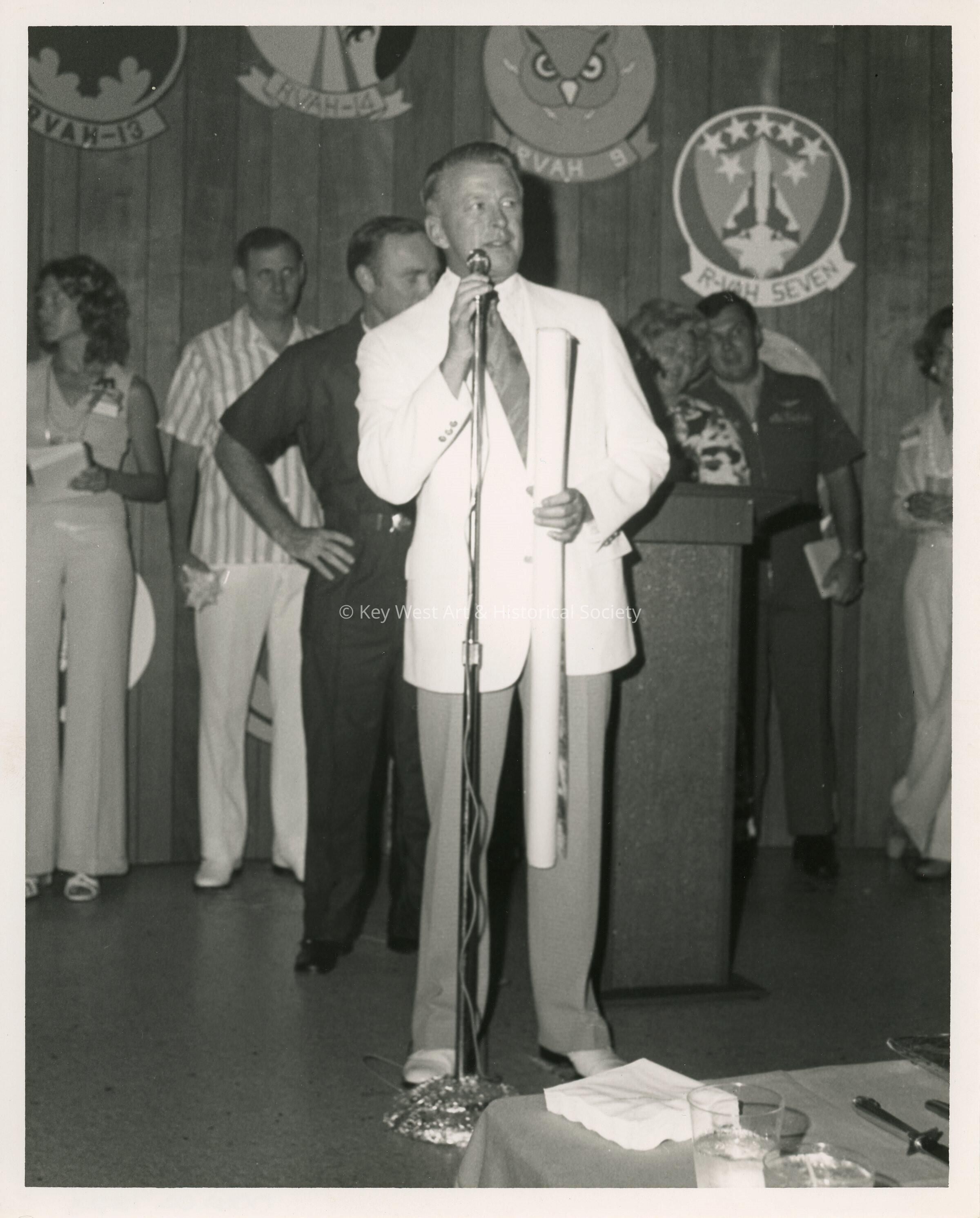 An unknown man speaking in a microphone at a ceremony