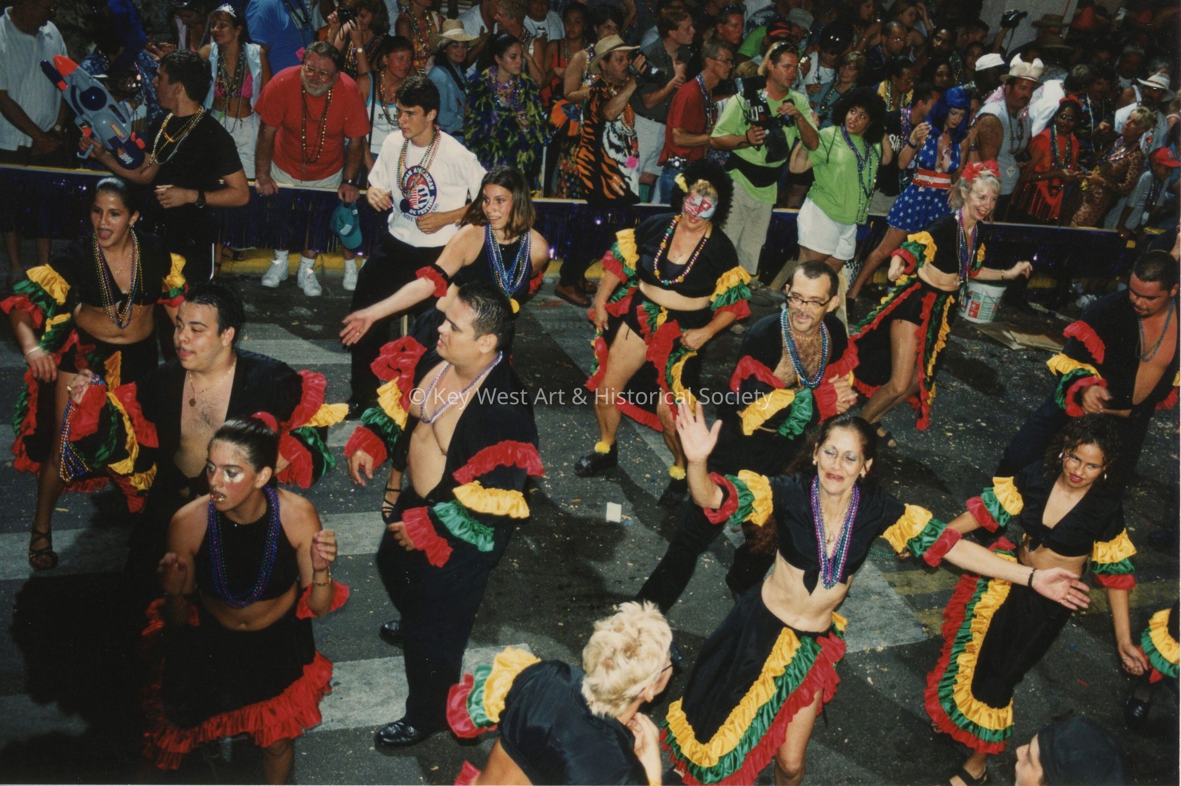 A group of unknown people dressed up dancing in the street for the parade.