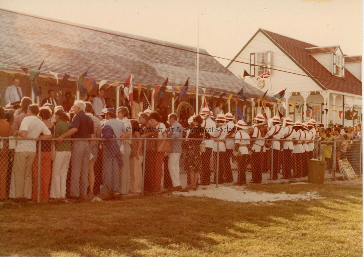 An unknown group of people standing against a fence