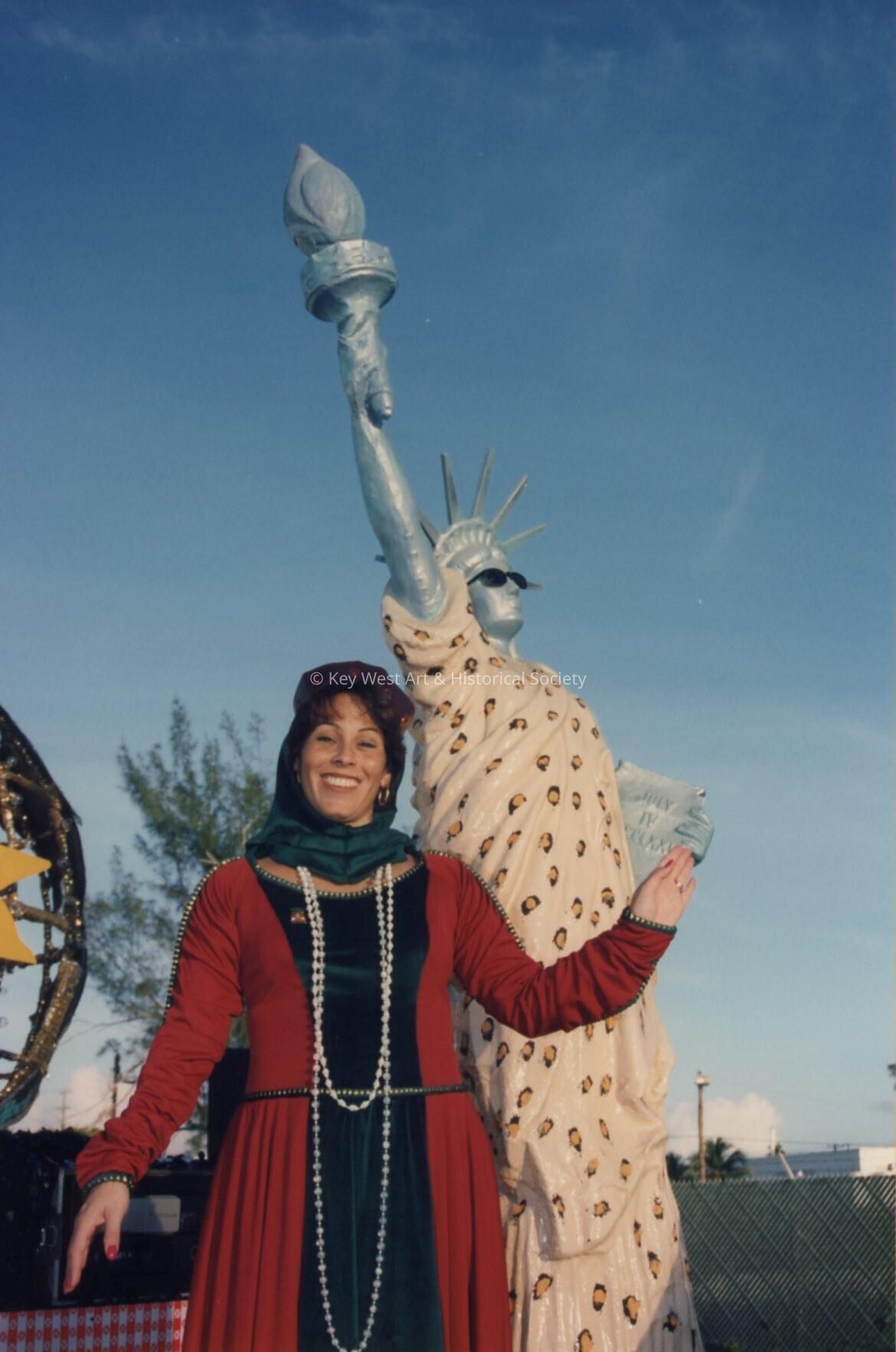 An unknown lady dressed up standing next to a float that has a statue of li