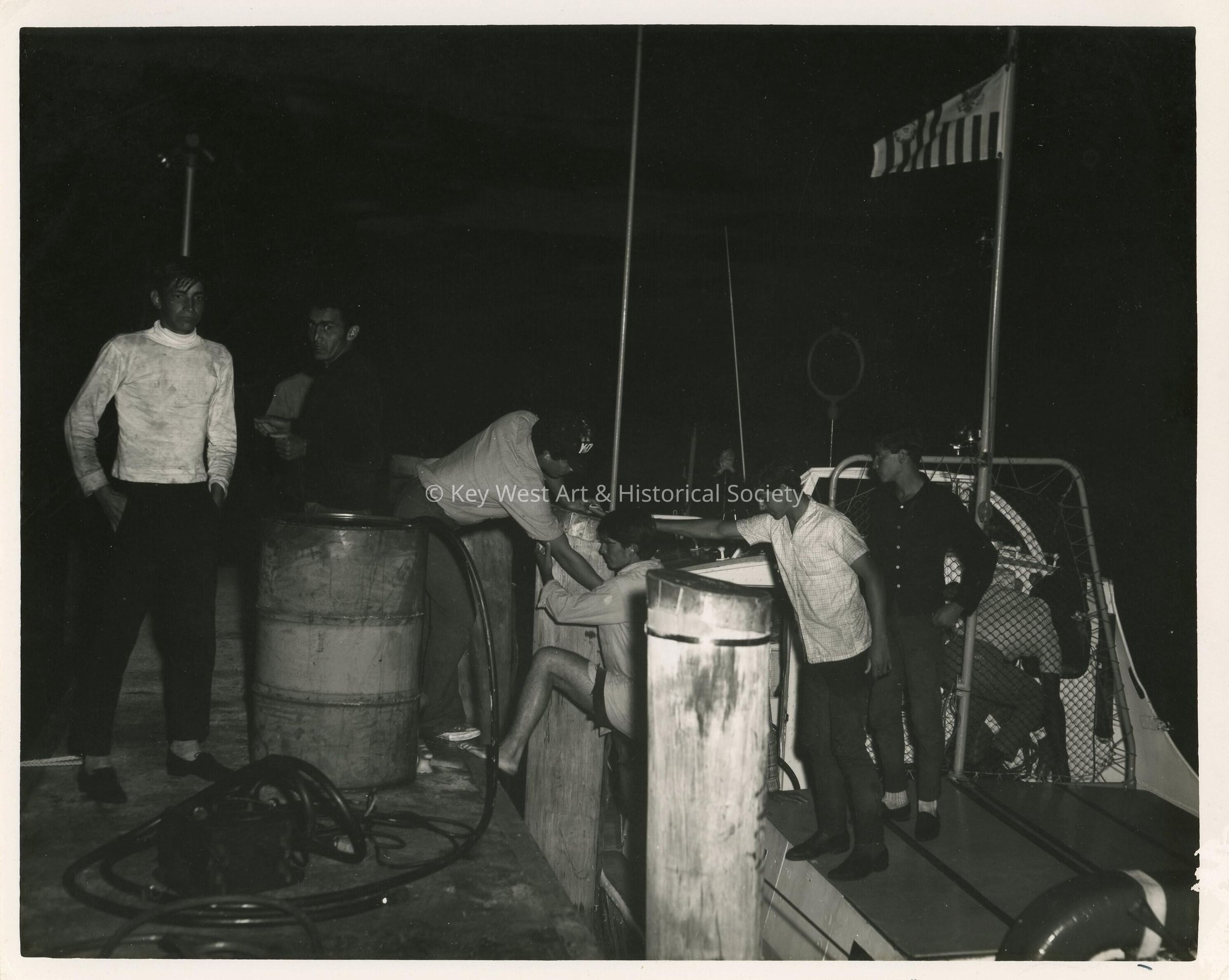 A group of unknown men on a boat jumping on to another boat