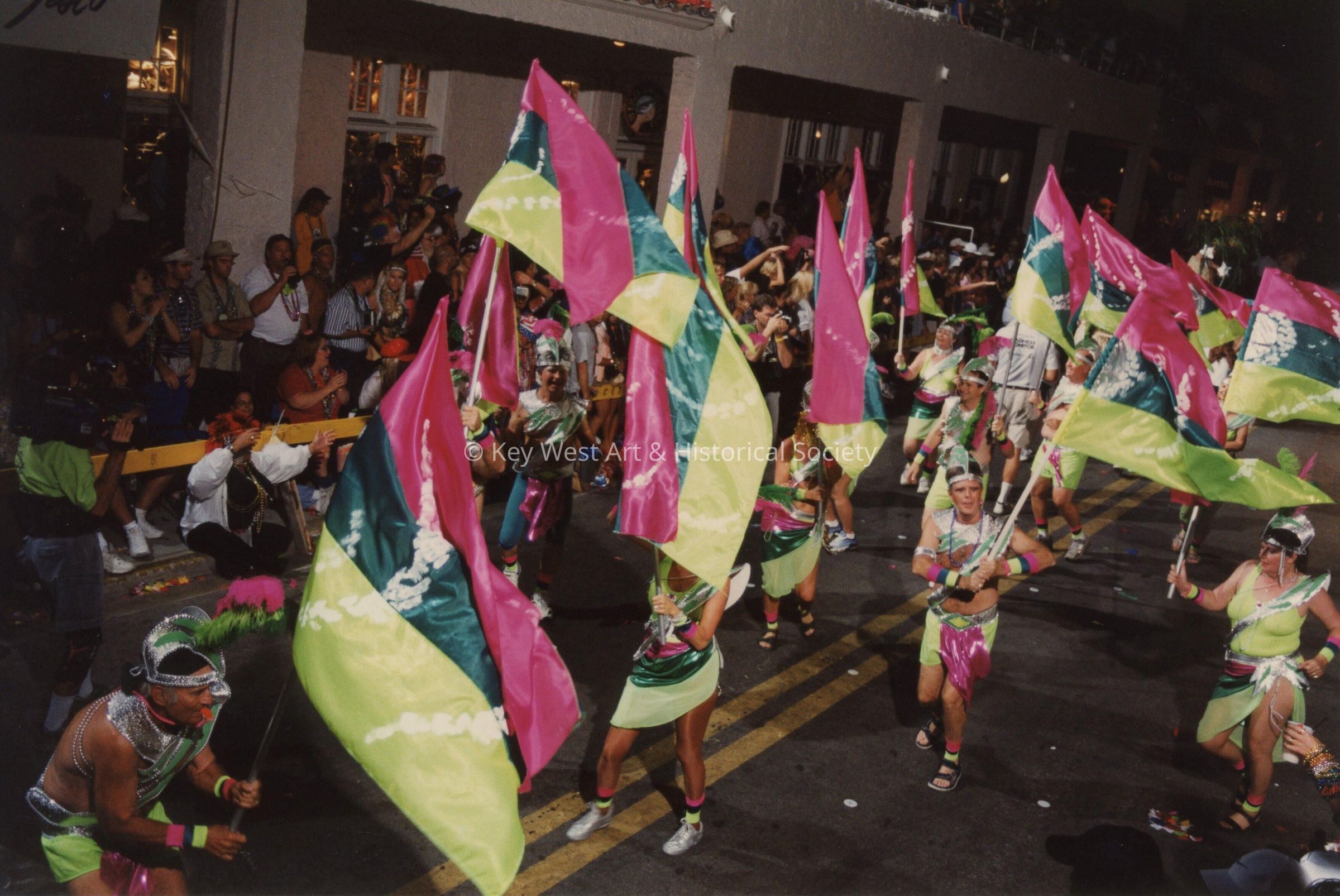 An unknown group of people dressed up walking in the street for the parade.