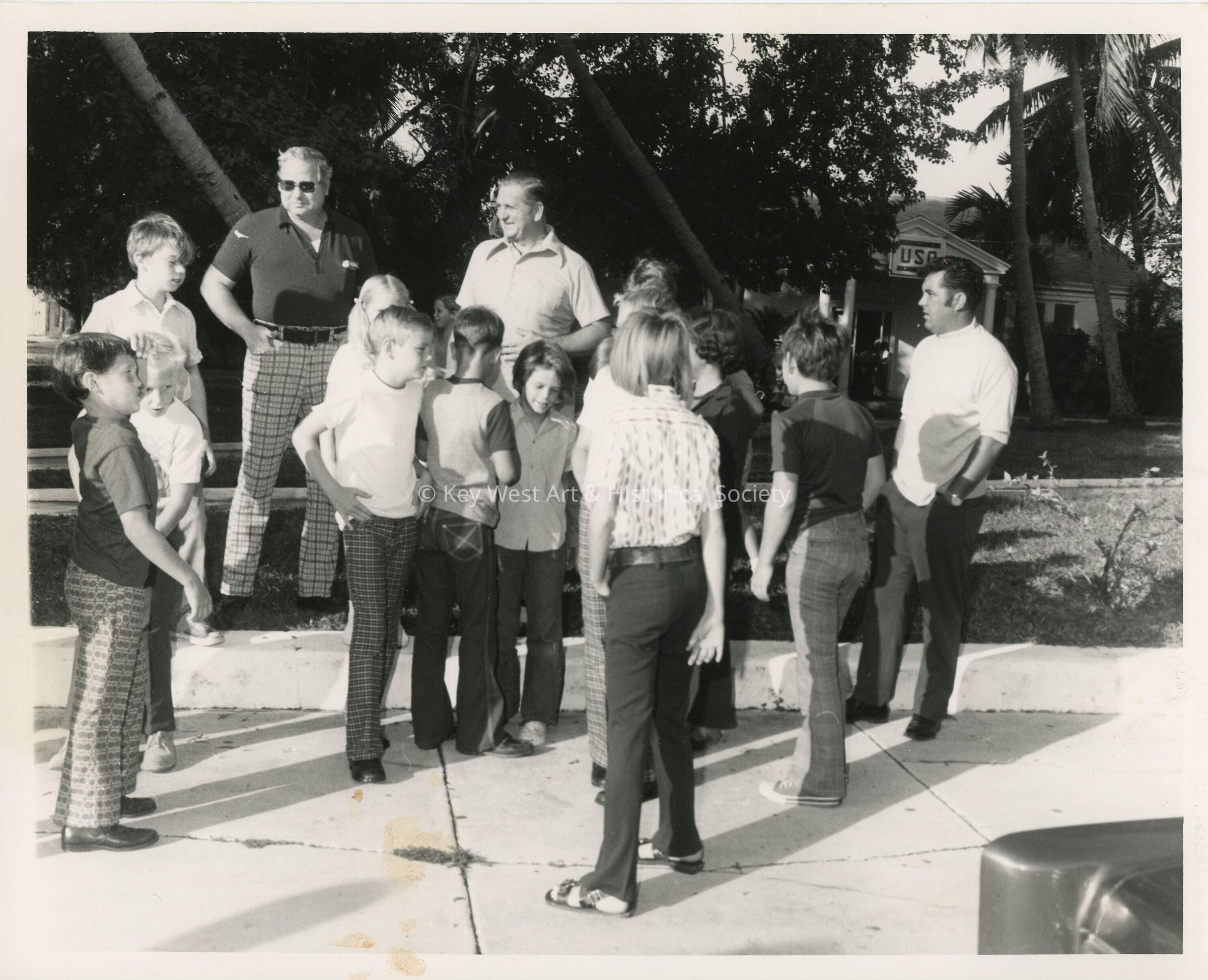 A group of unknown adults and children standing outside