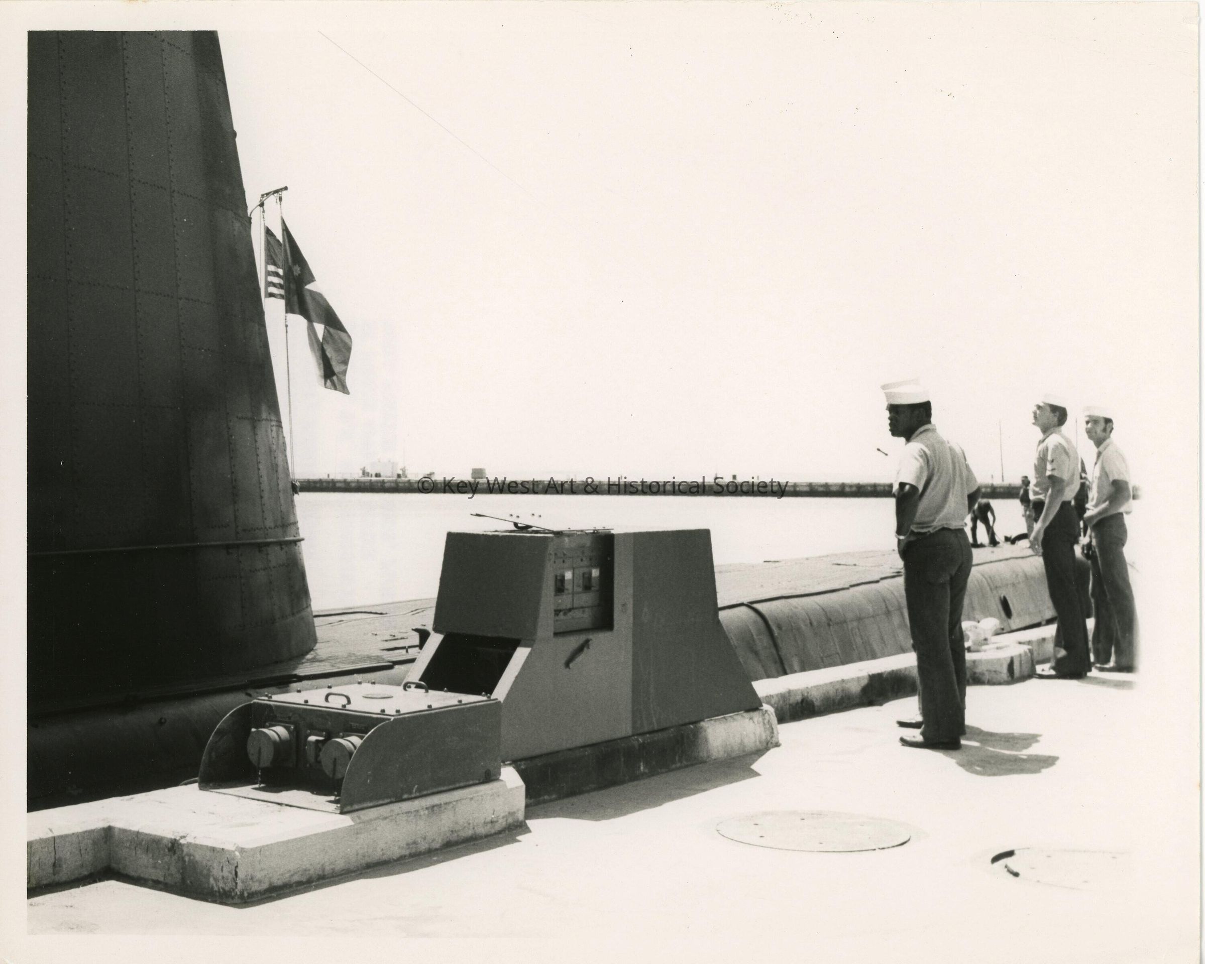 A submarine with men in uniform standing near by