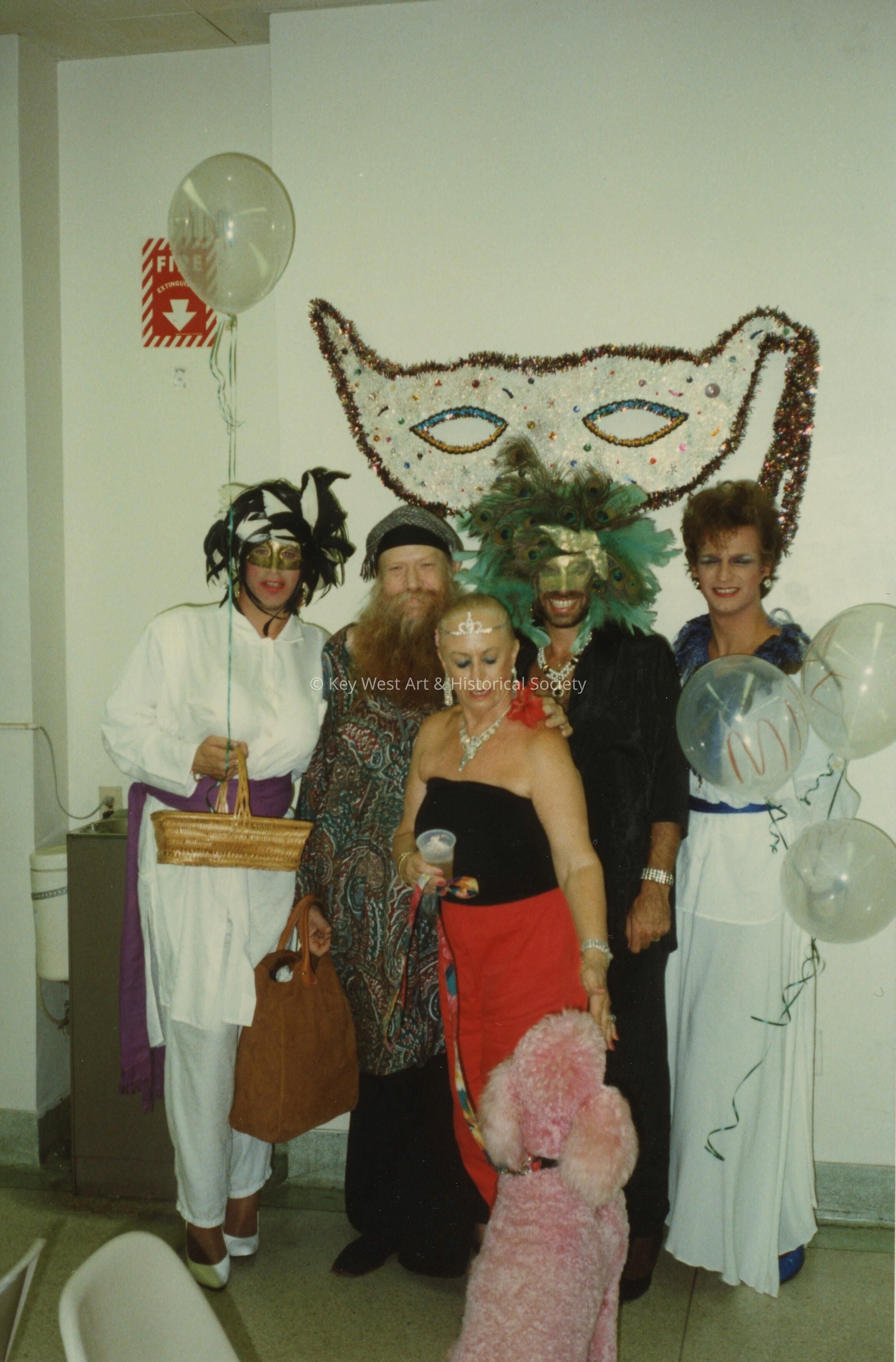 A group of unknown people dressed up and an pink poodle.