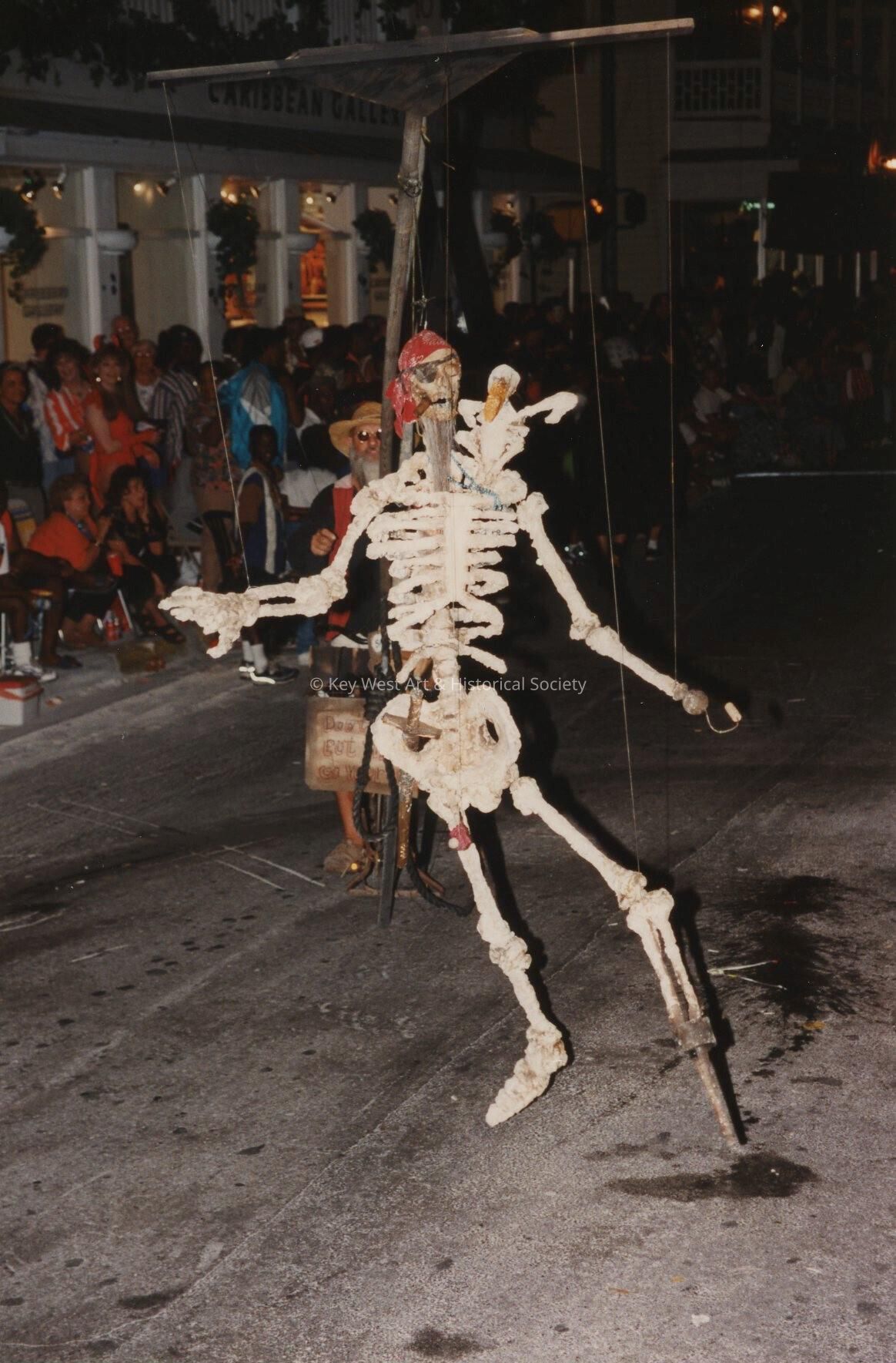 An unknown man on a bike holding a skeleton.