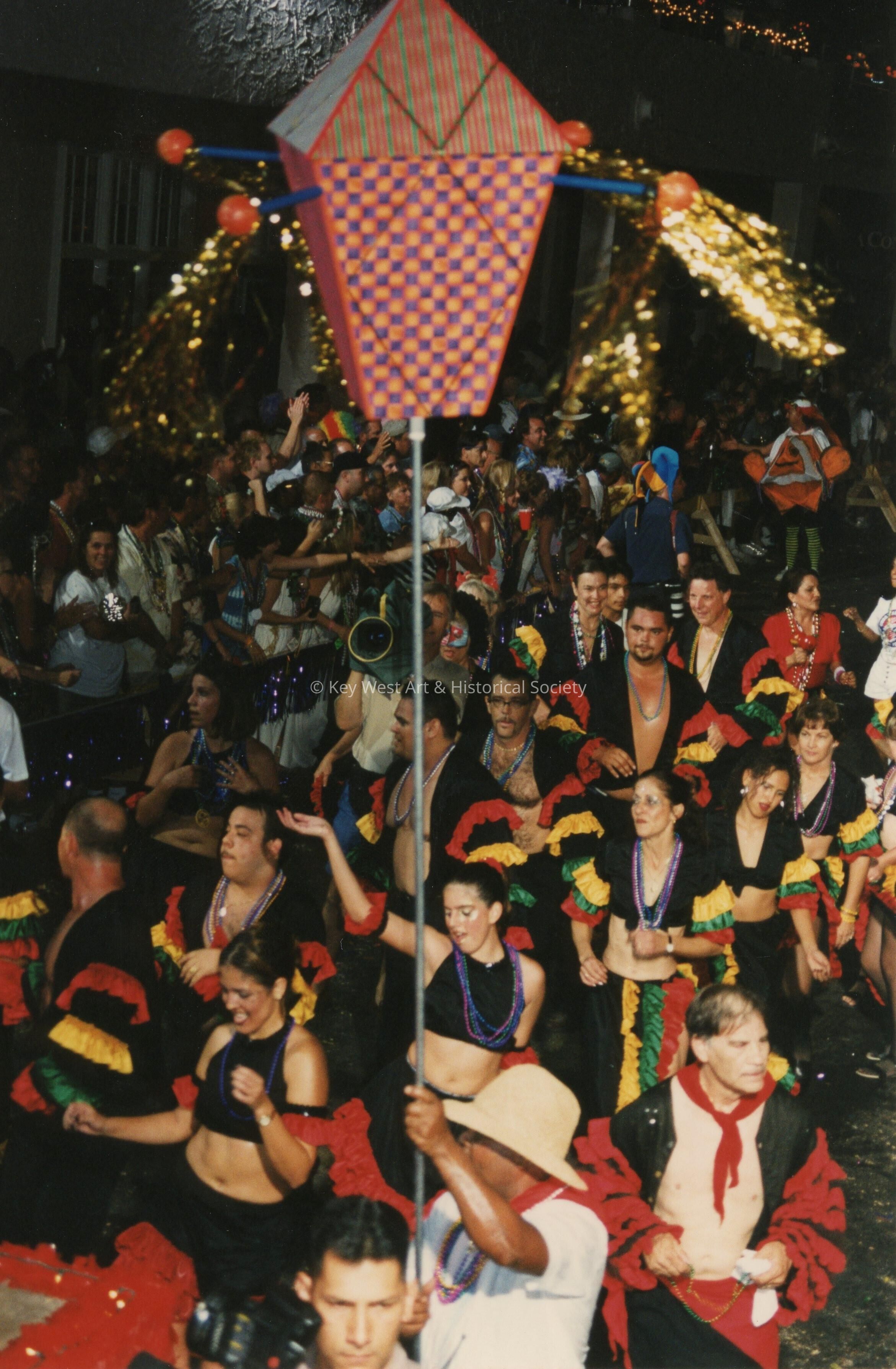 A group of unknown people dressed up dancing in the street for the parade.