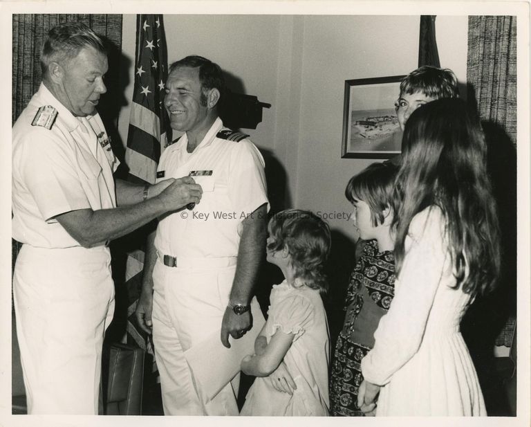 2 Men in uniform at a party with a family standing near by