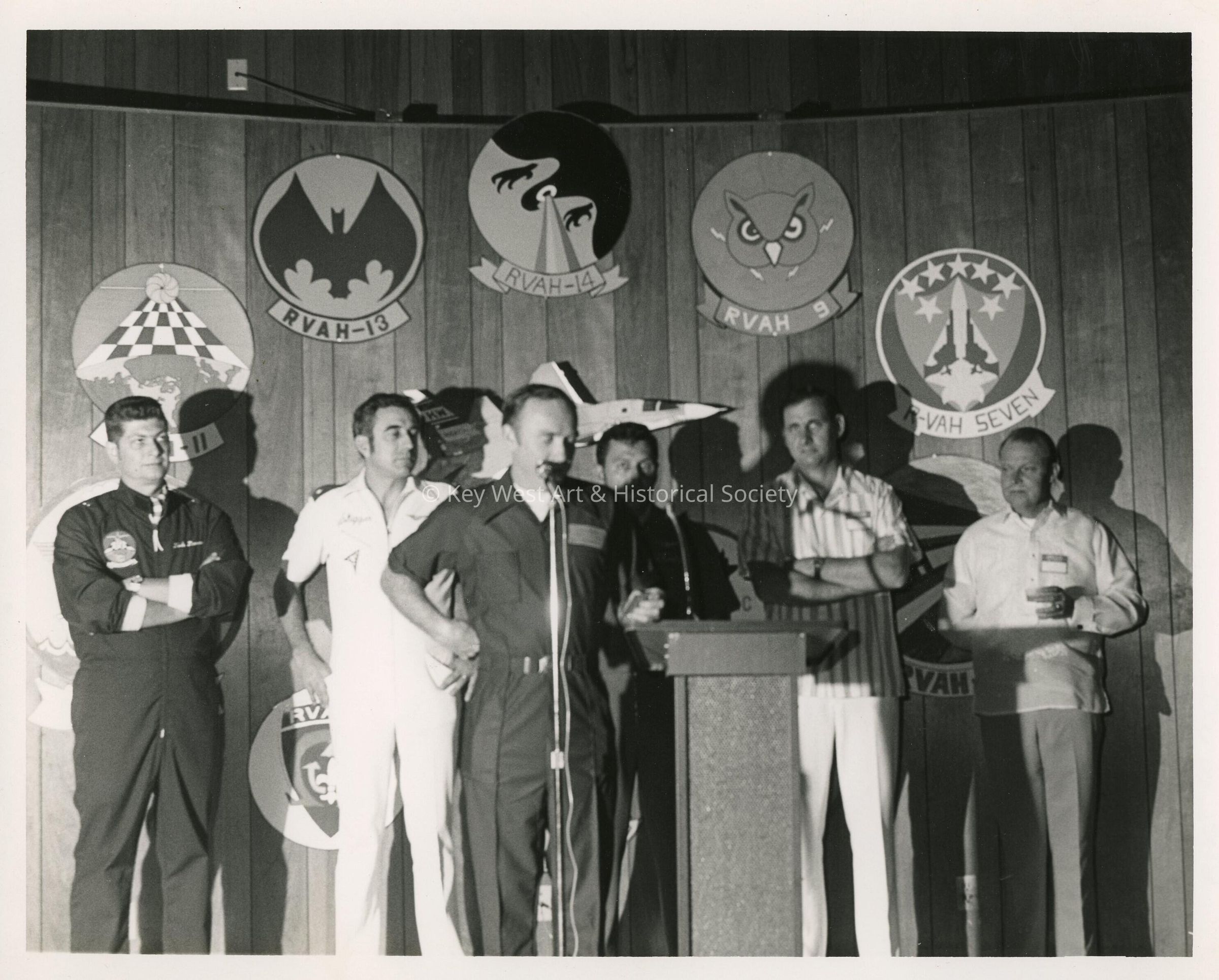 A group of men at a ceremony talking at the microphone