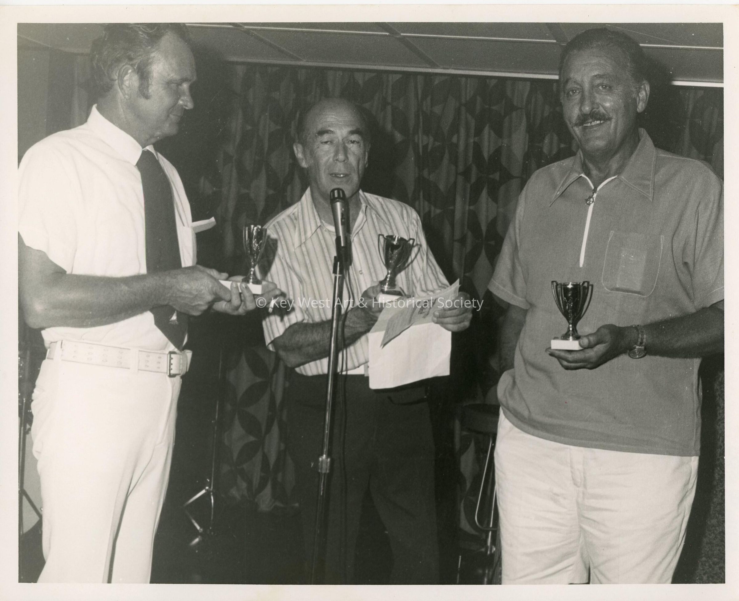 3 Unknown men each holding a trophy