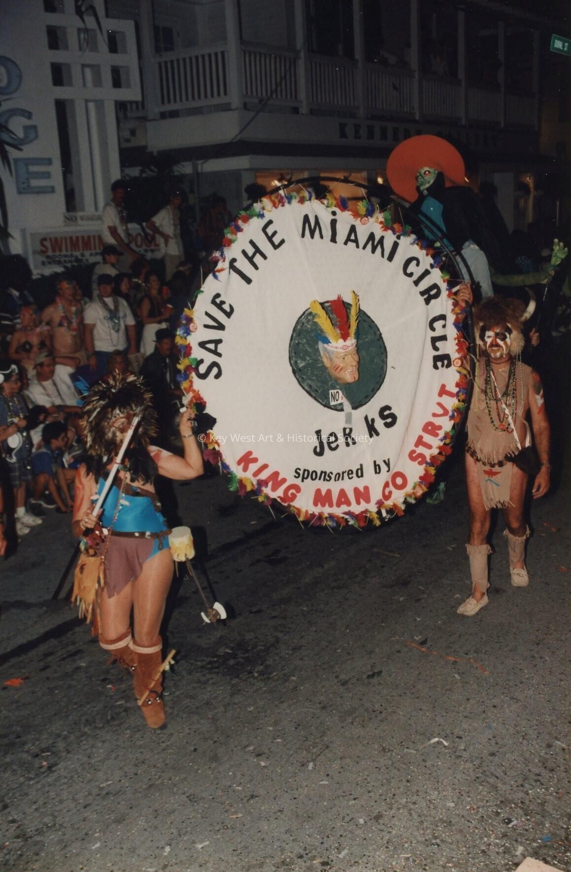 A group of unknown people in the parade holding a sign that reads Save the