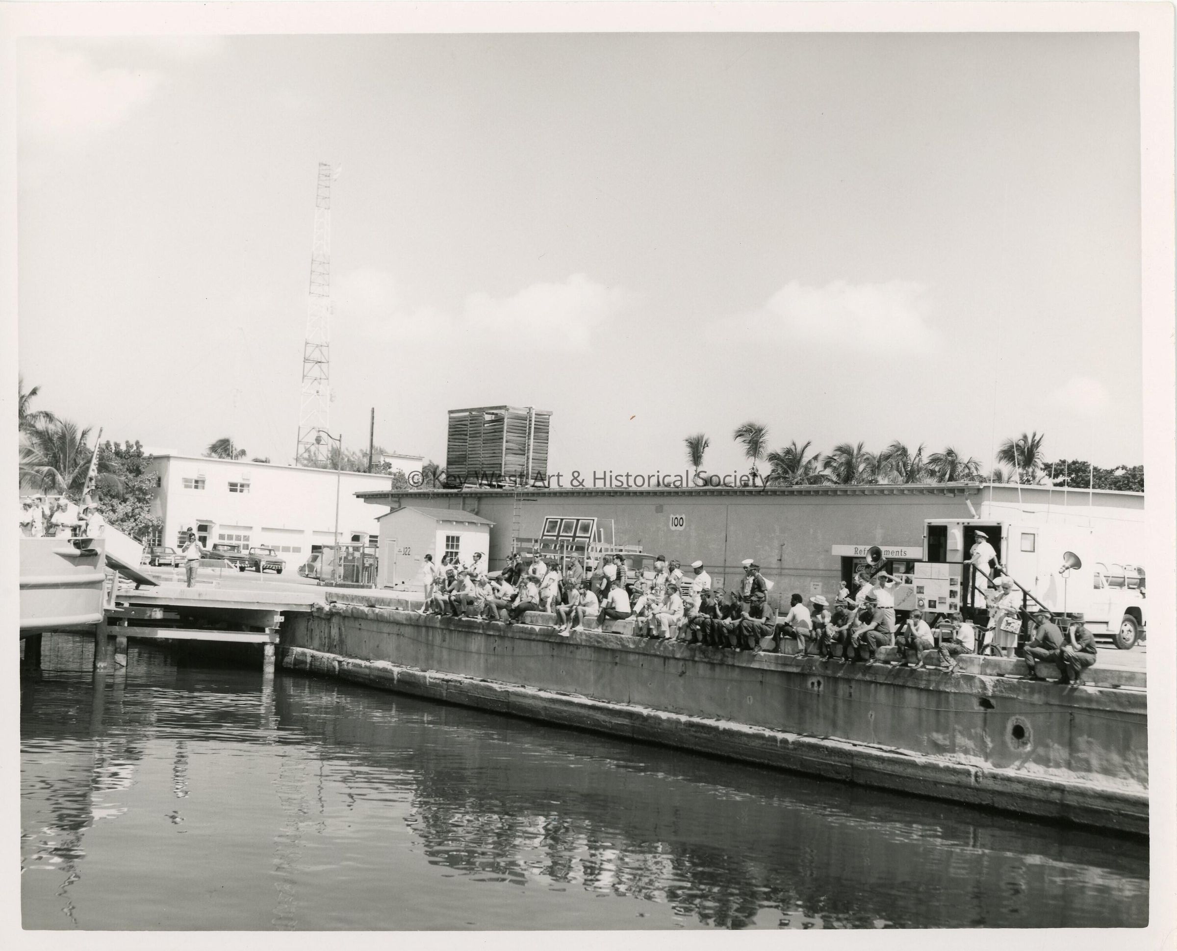 A group of unknown people sitting on a pier