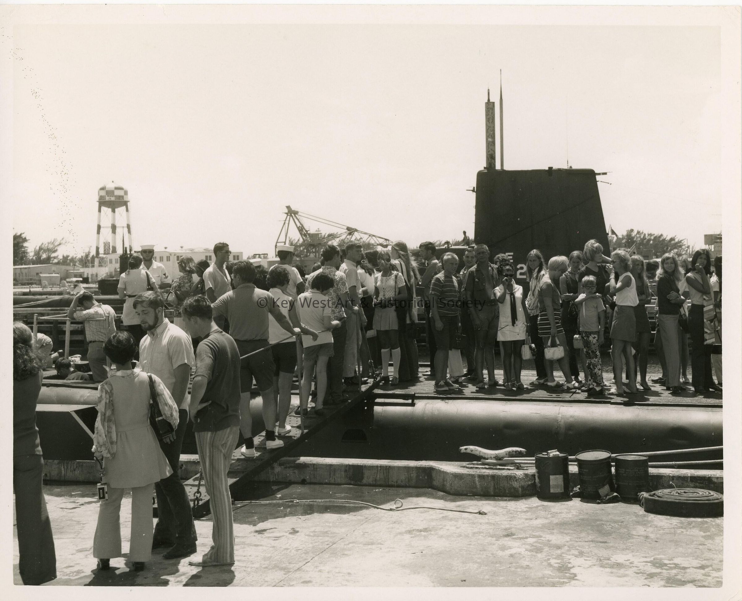 A big crowd of unknown people standing near a ship