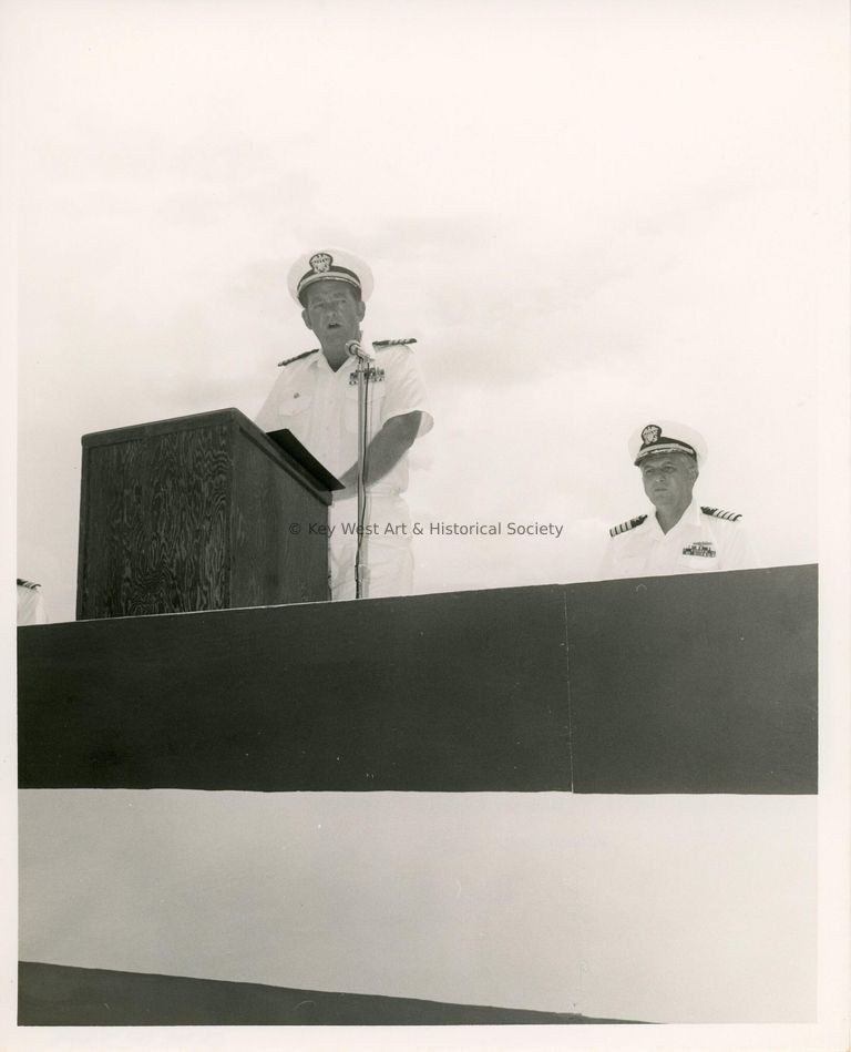 2 Men in uniform talking at the podium