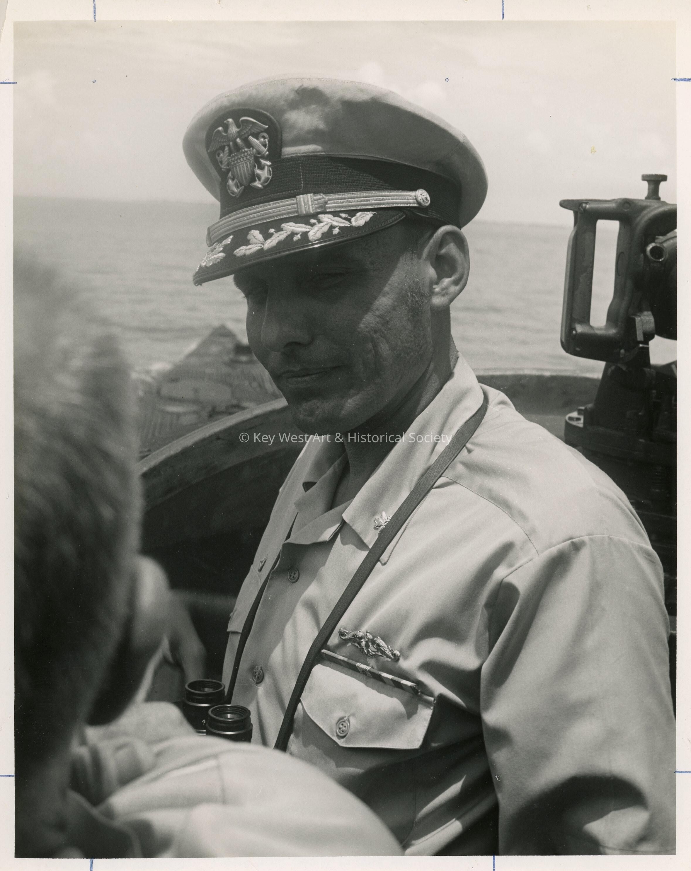 An unknown man in uniform in a ship holding binoculars