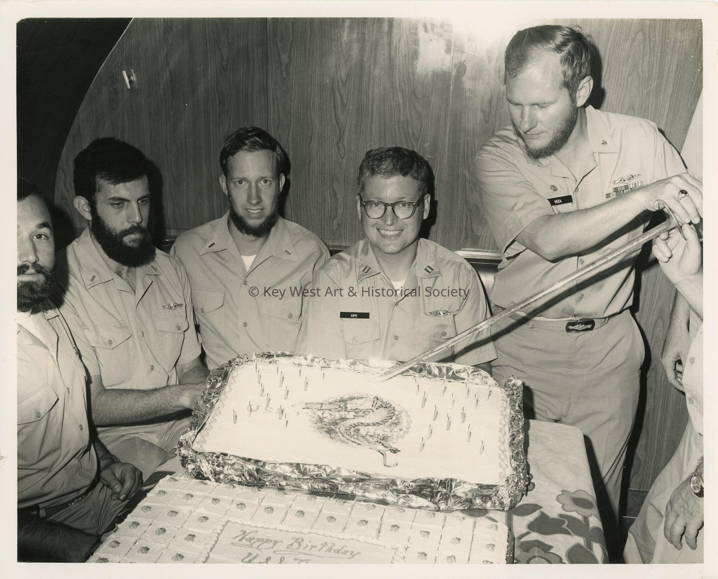 A group of unknown men in uniform with a cake