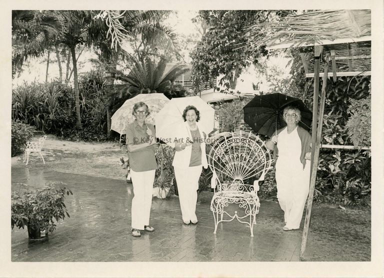 3 Unknown woman holding umbrellas while they stand in the rain