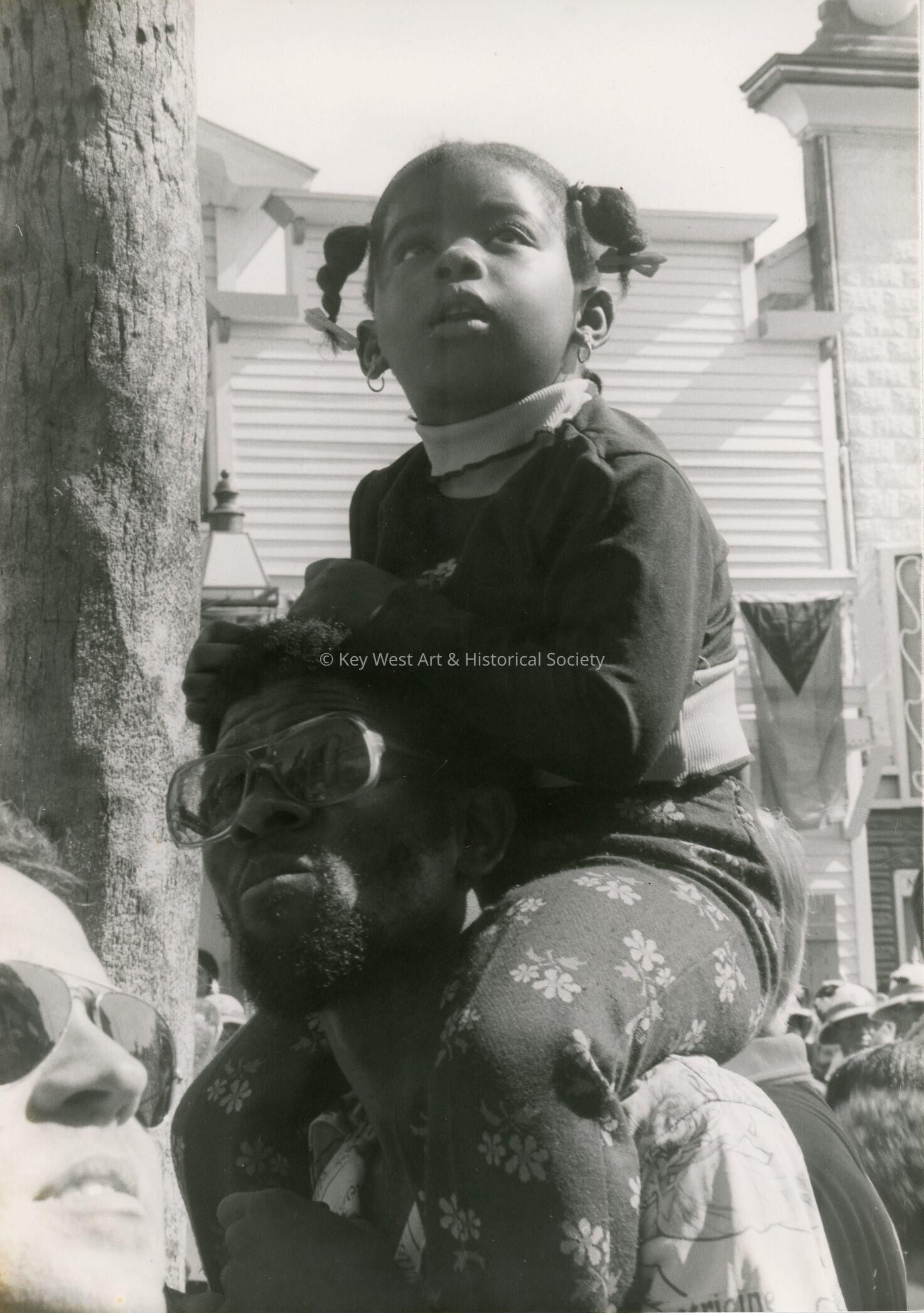 An unknown child sitting on a mans shoulders