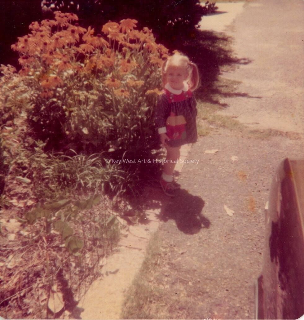 A little girl standing in a yard