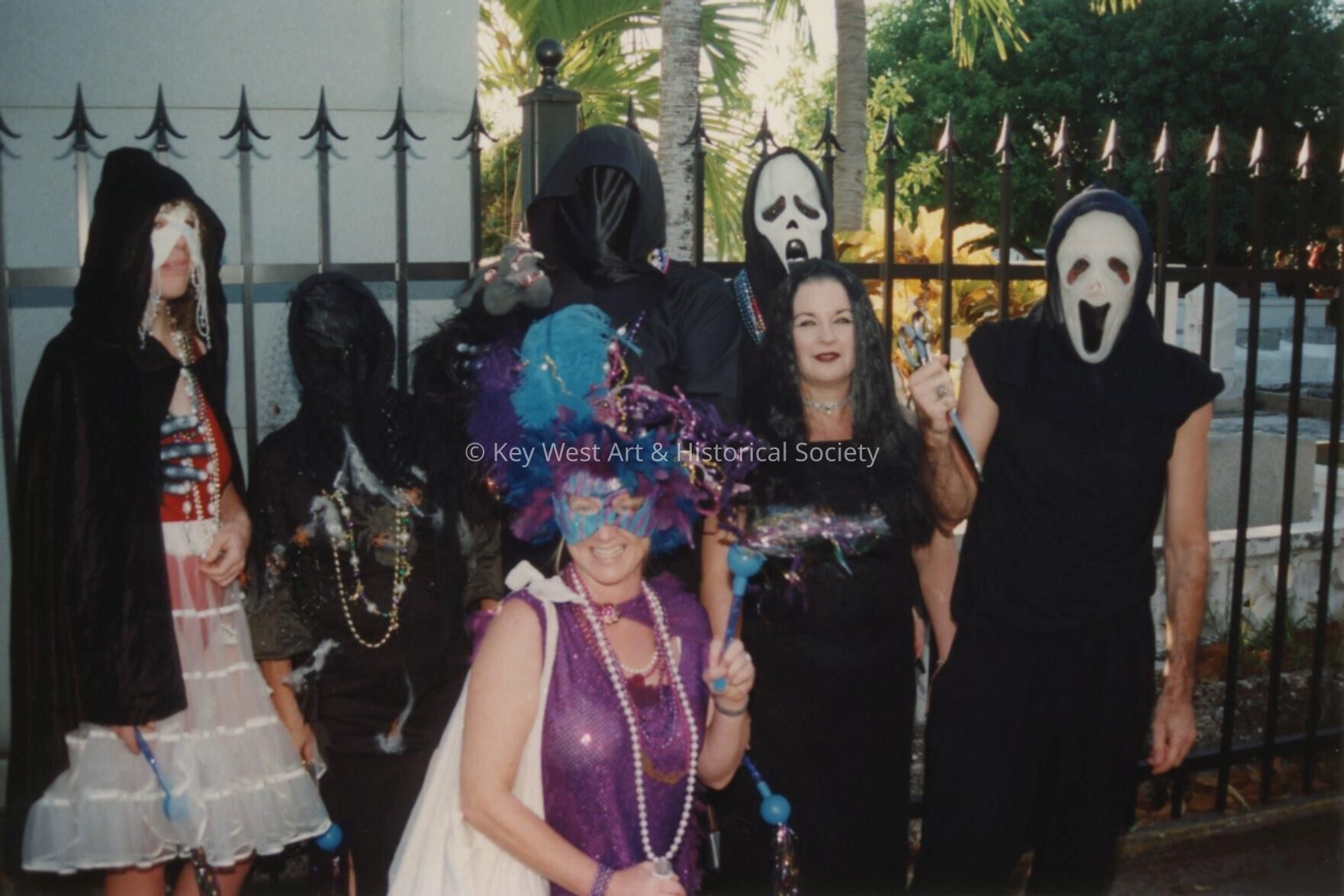 A group of unknown people dressed up next to the cemetery.