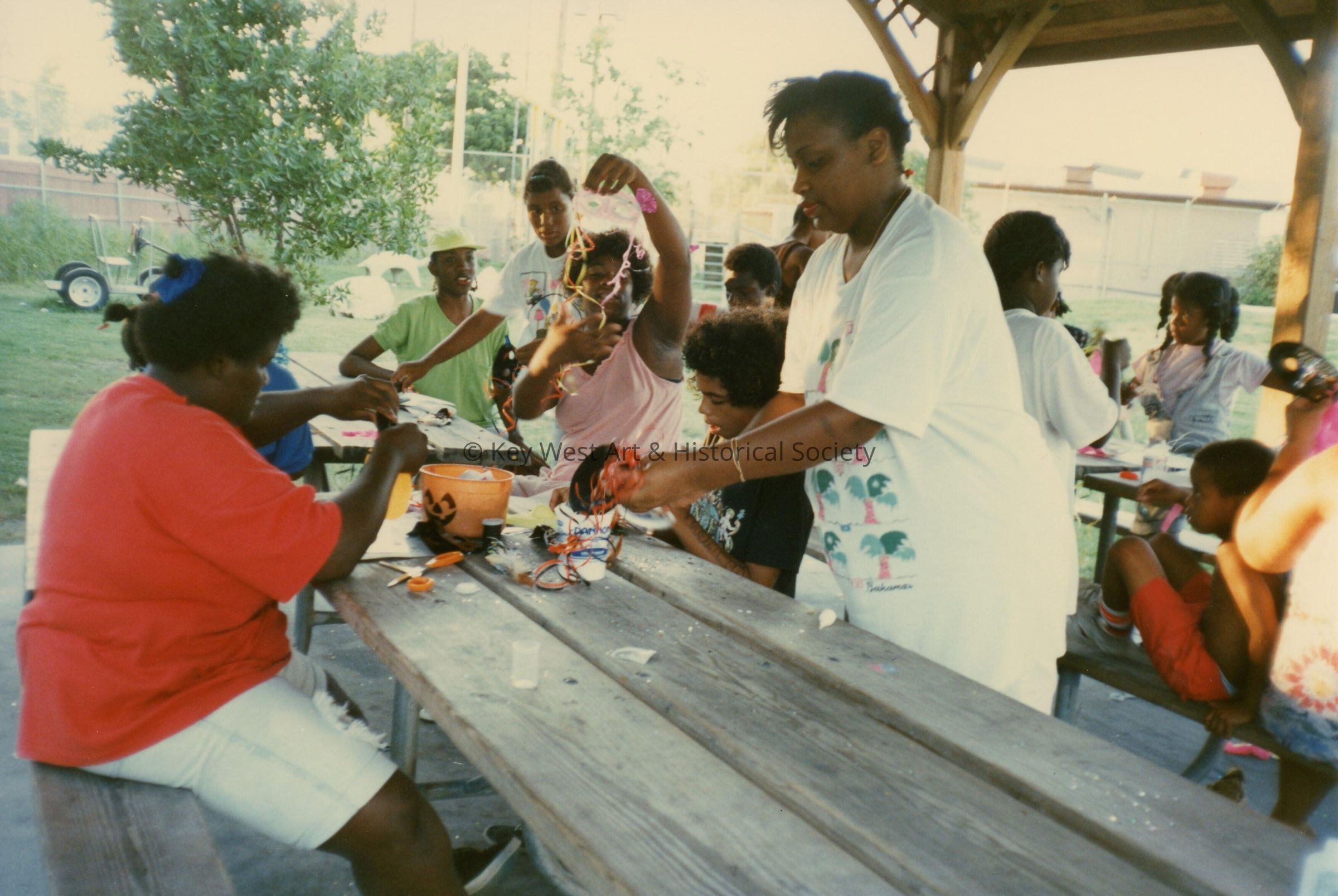 A group of unknown people working outside on a table on crafts.