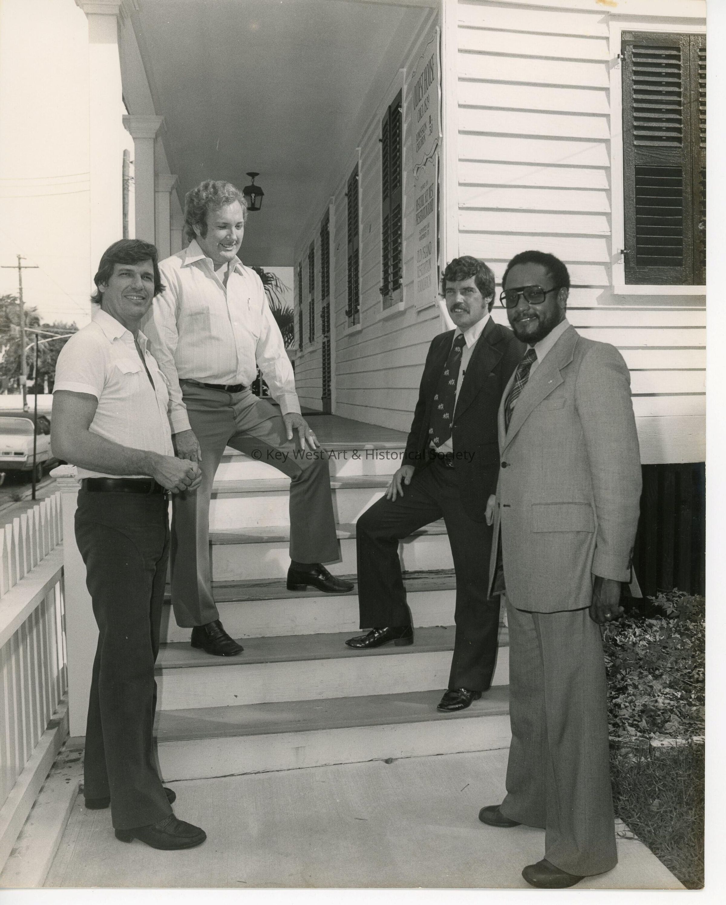 4 Unknown men standing on the stairway at a museum