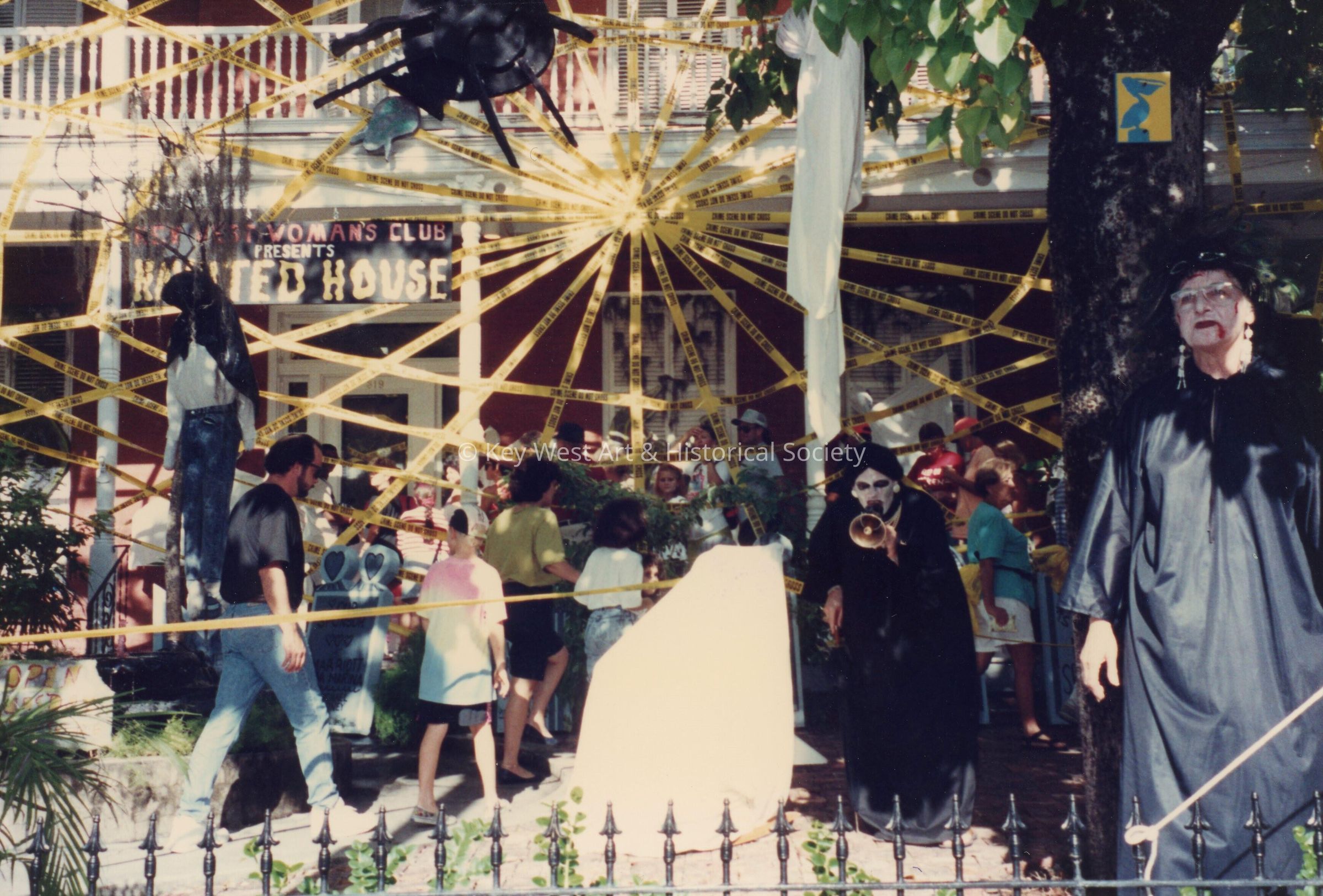 A group of unknown people standing in the front yard at the Woman's Club.