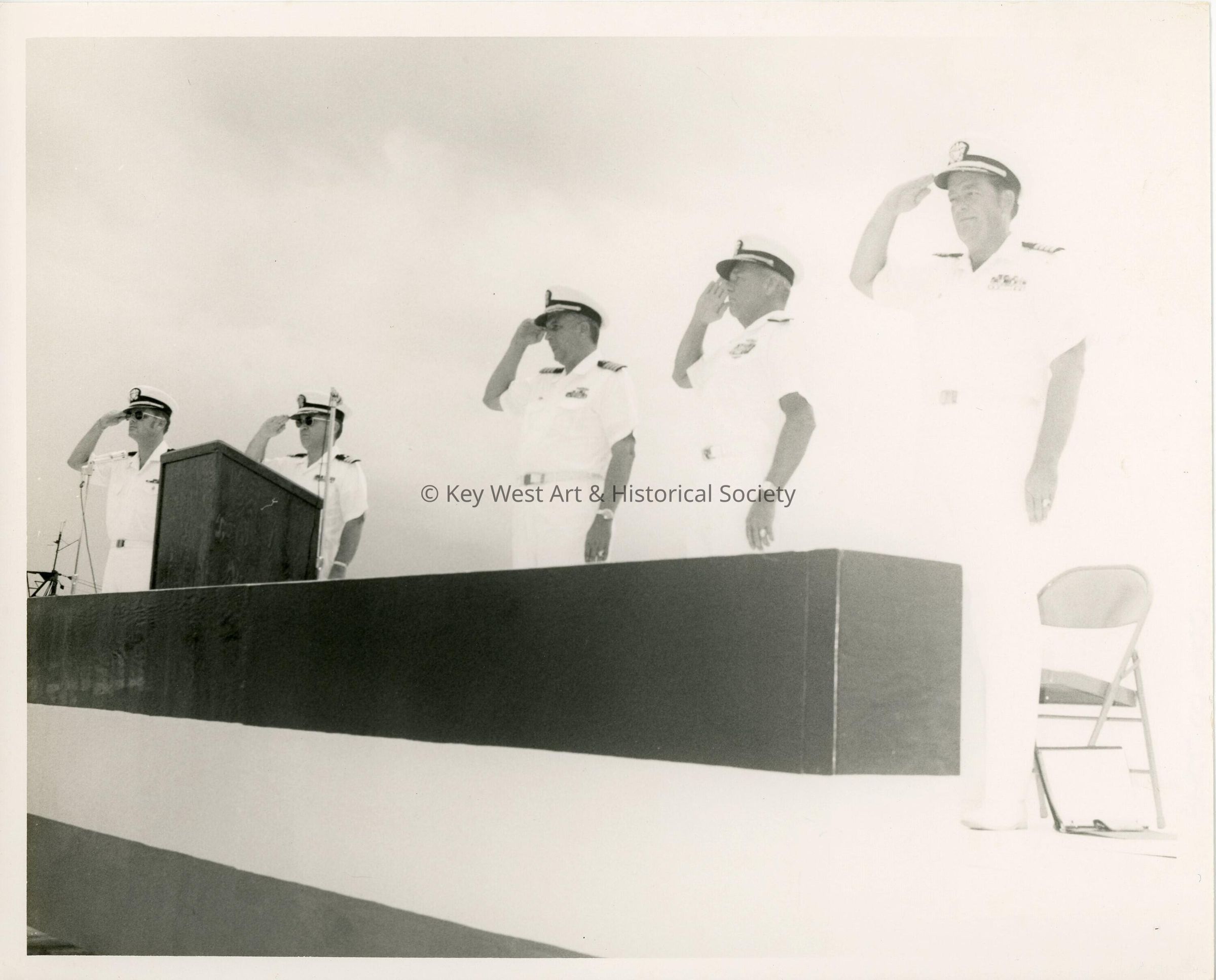A group of men in uniform standing at attention near a podium