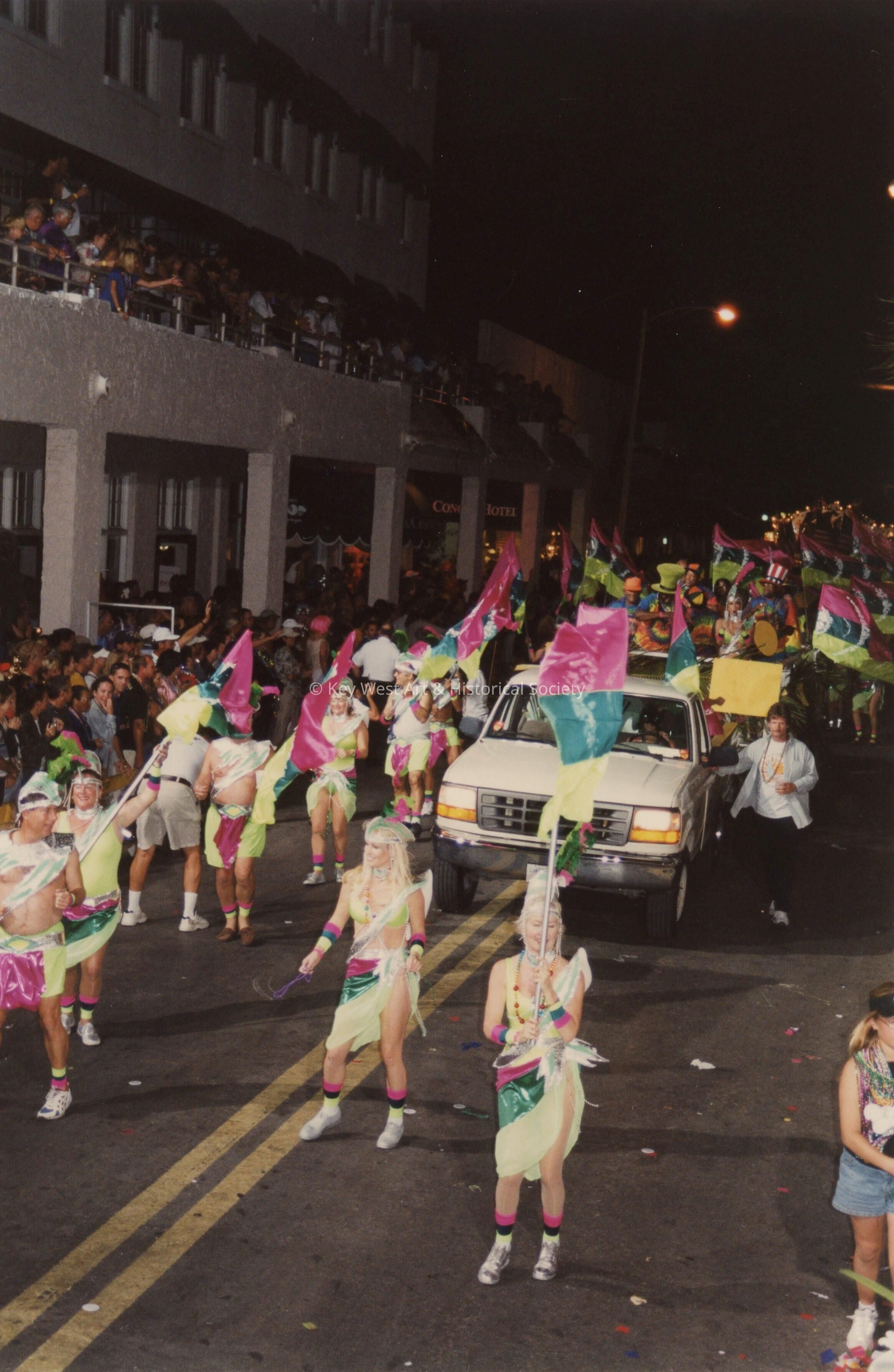 An unknown group of people dressed up walking in the street for the parade.