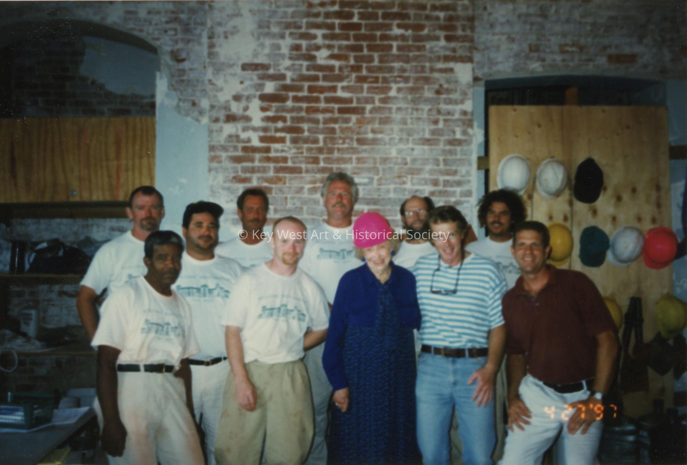 A group of unknown men standing with Wilhelmina Harvey inside of the Custom