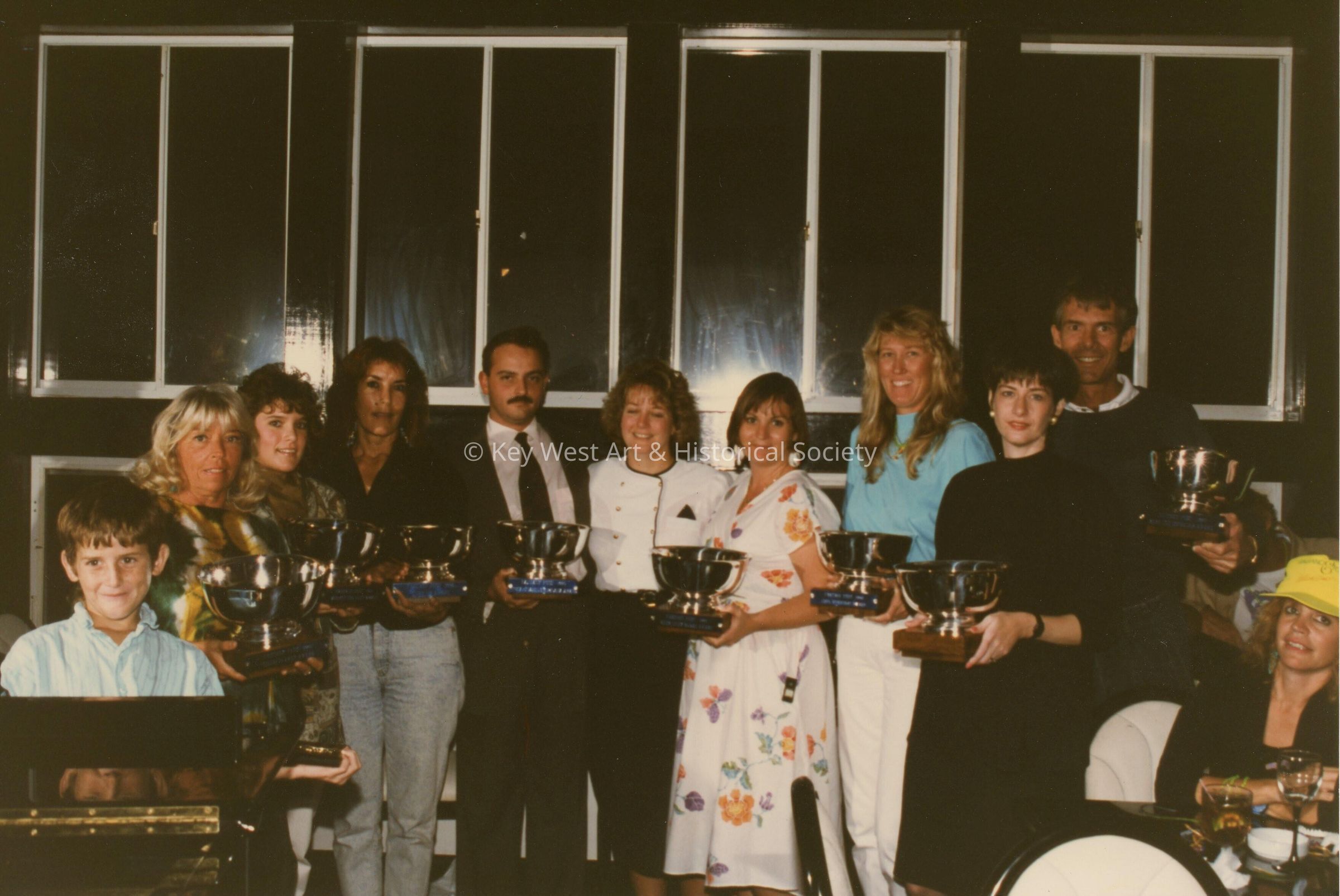A group of unknown people holding trophy's.
