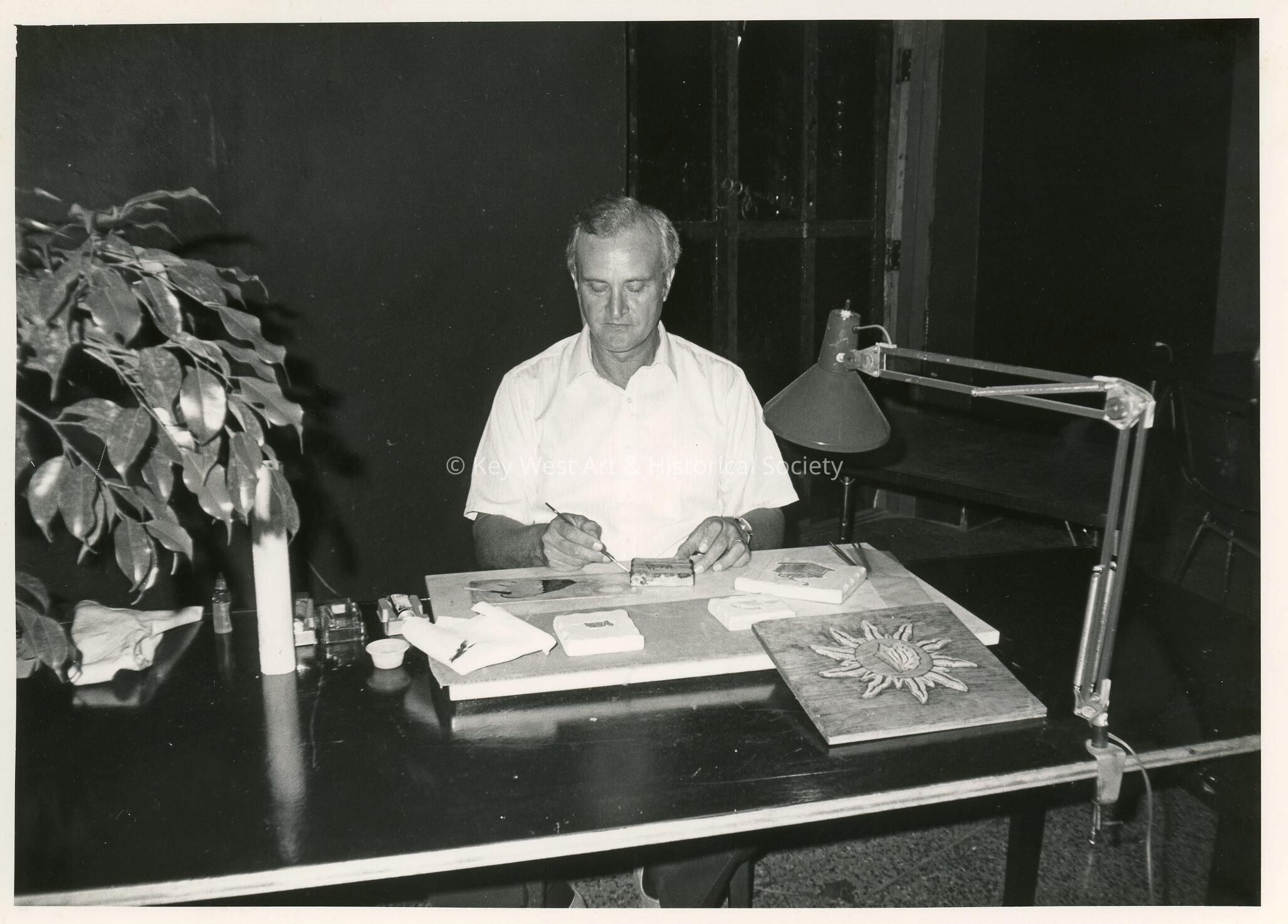An unknown man at a desk working on artwork