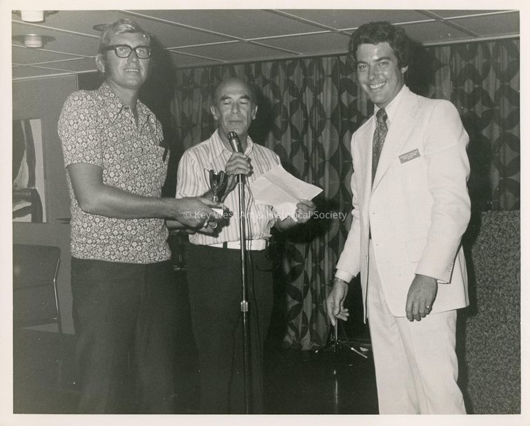 3 Unknown men standing at a microphone